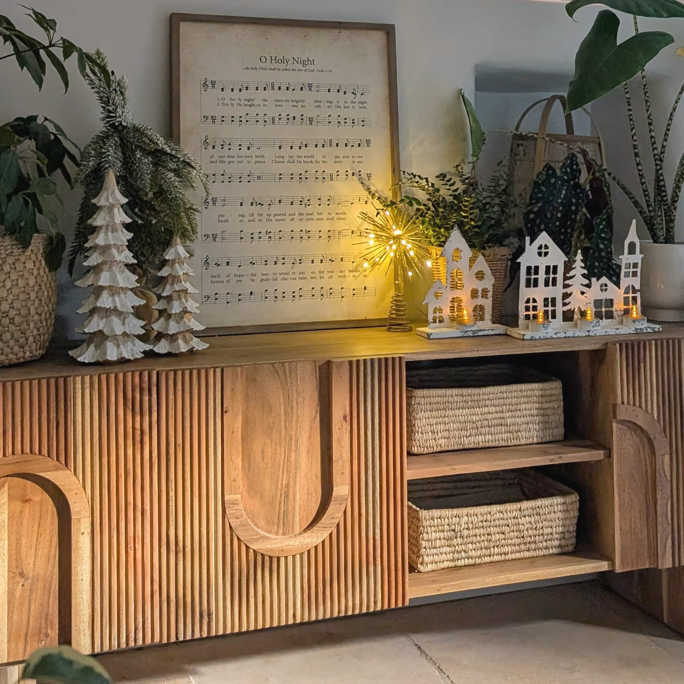 Buffet en bois avec décorations de Noël, maisons en bois blanches et sapins éclairés par LED