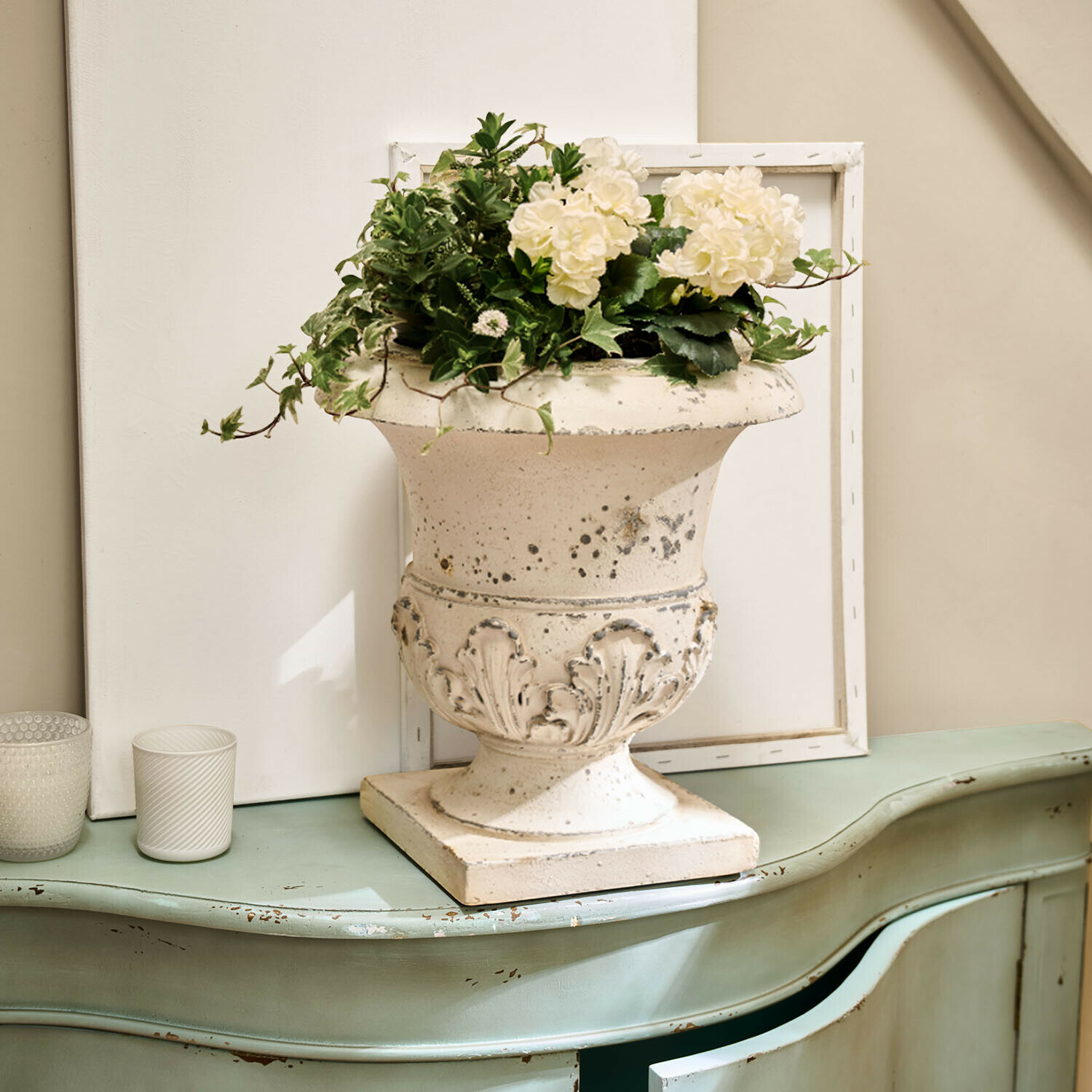 Vase en céramique blanche avec décoration florale sur commode verte vieillie style vintage