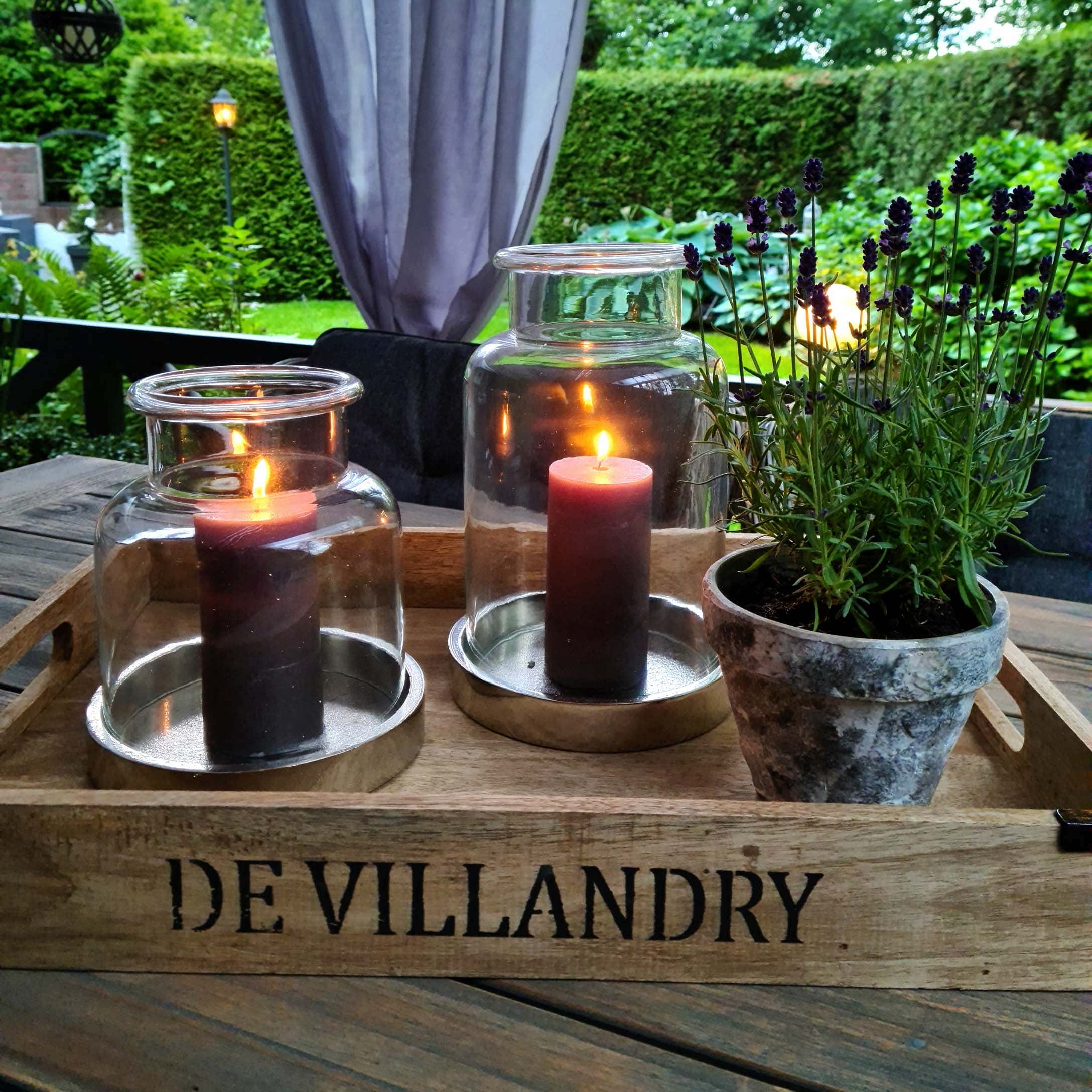 Plateau en bois avec deux lanternes en verre et un pot de lavande sur une table en bois dans un jardin