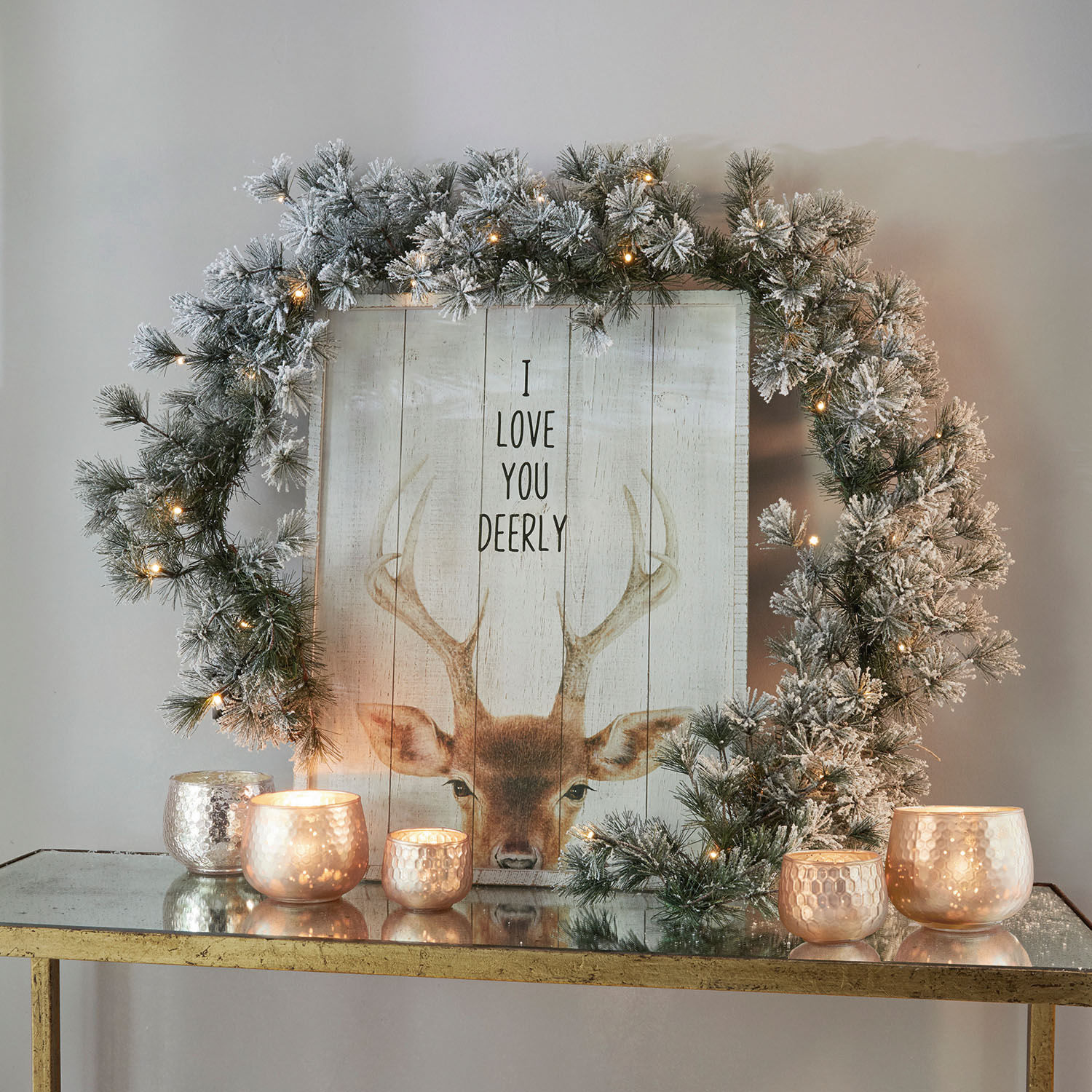 Guirlande Toni Couronne décorative enneigée avec guirlande lumineuse LED sur table dorée avec bougies