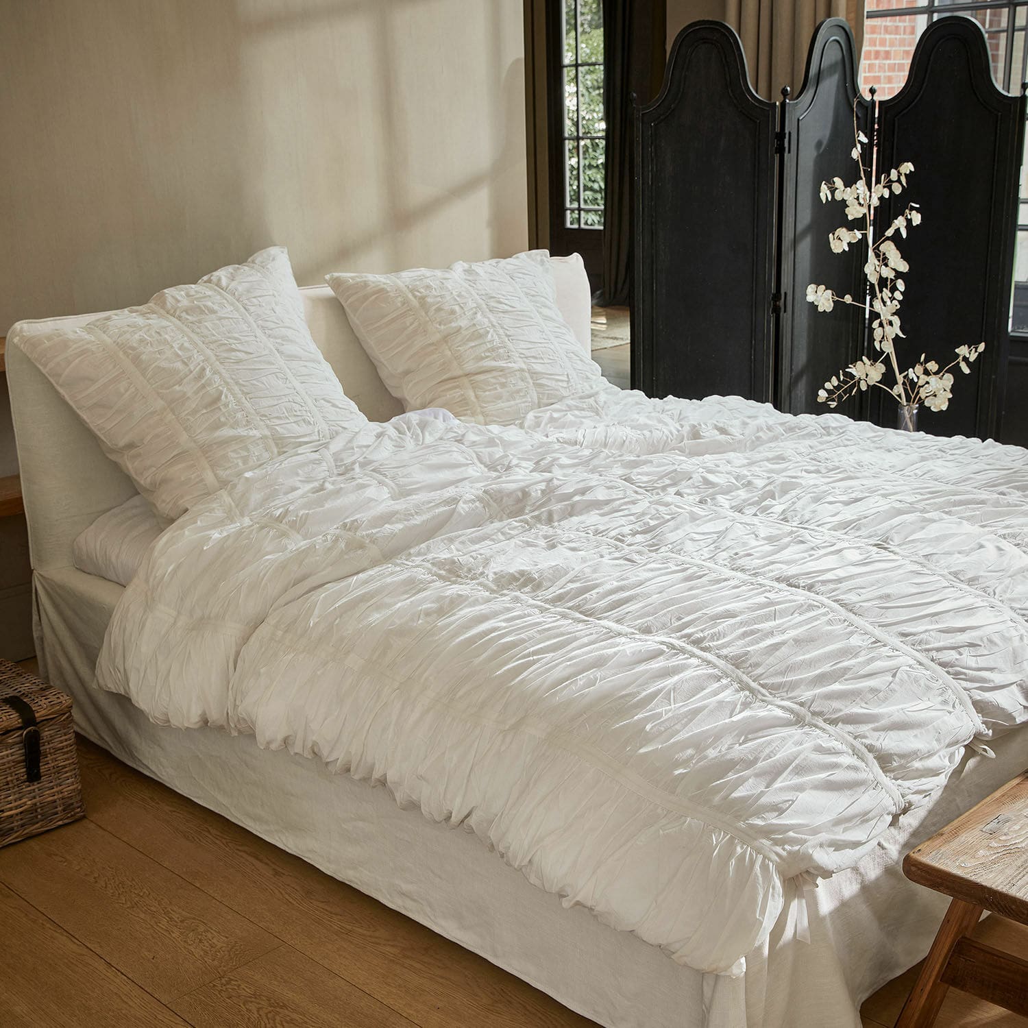 Parure de lit Magdelen Parure de lit blanche en coton froissé sur un lit dans une chambre chaleureuse