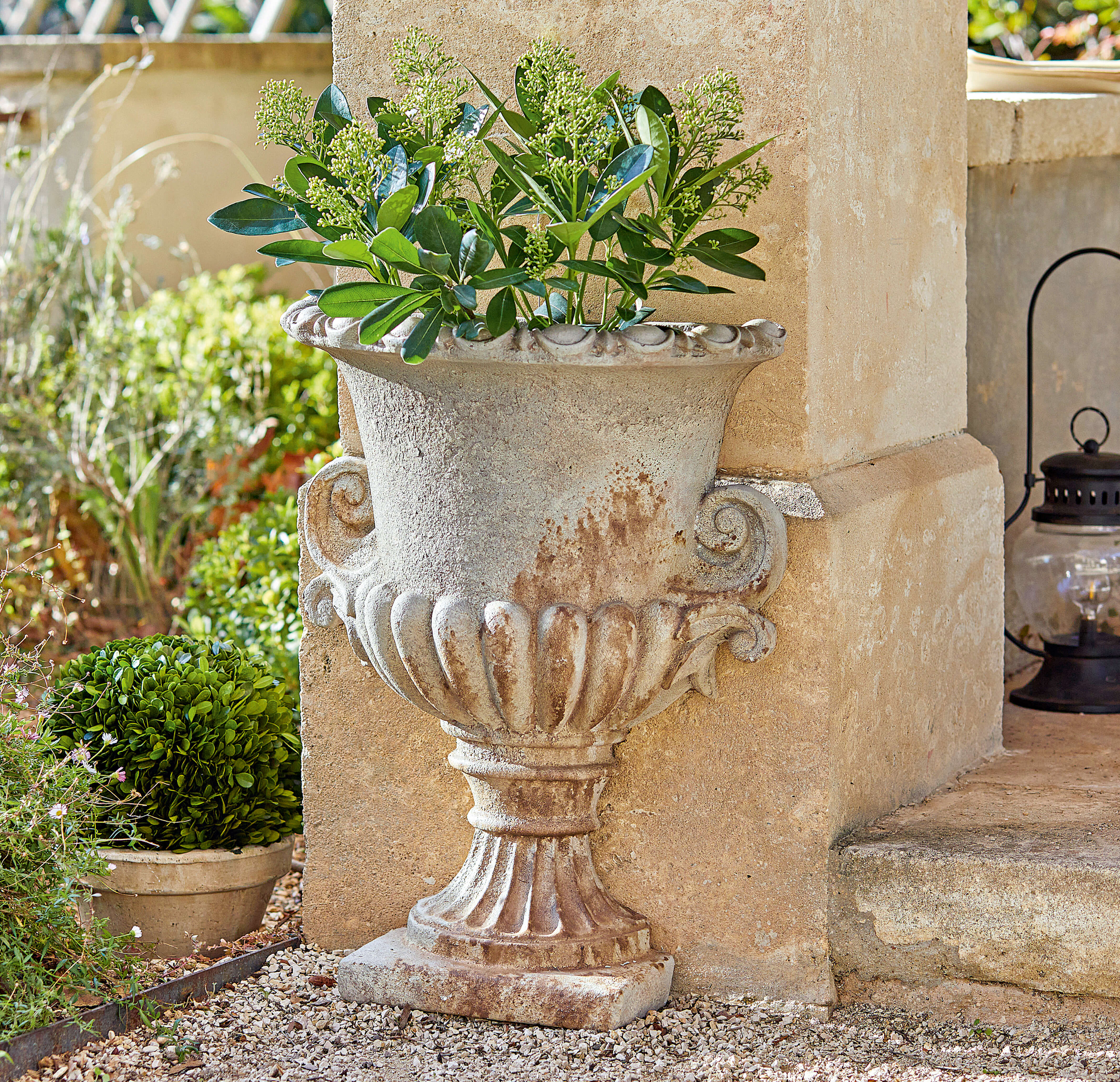 Vase décoratif en pierre de style antique avec plantes vertes, décoration extérieure élégante