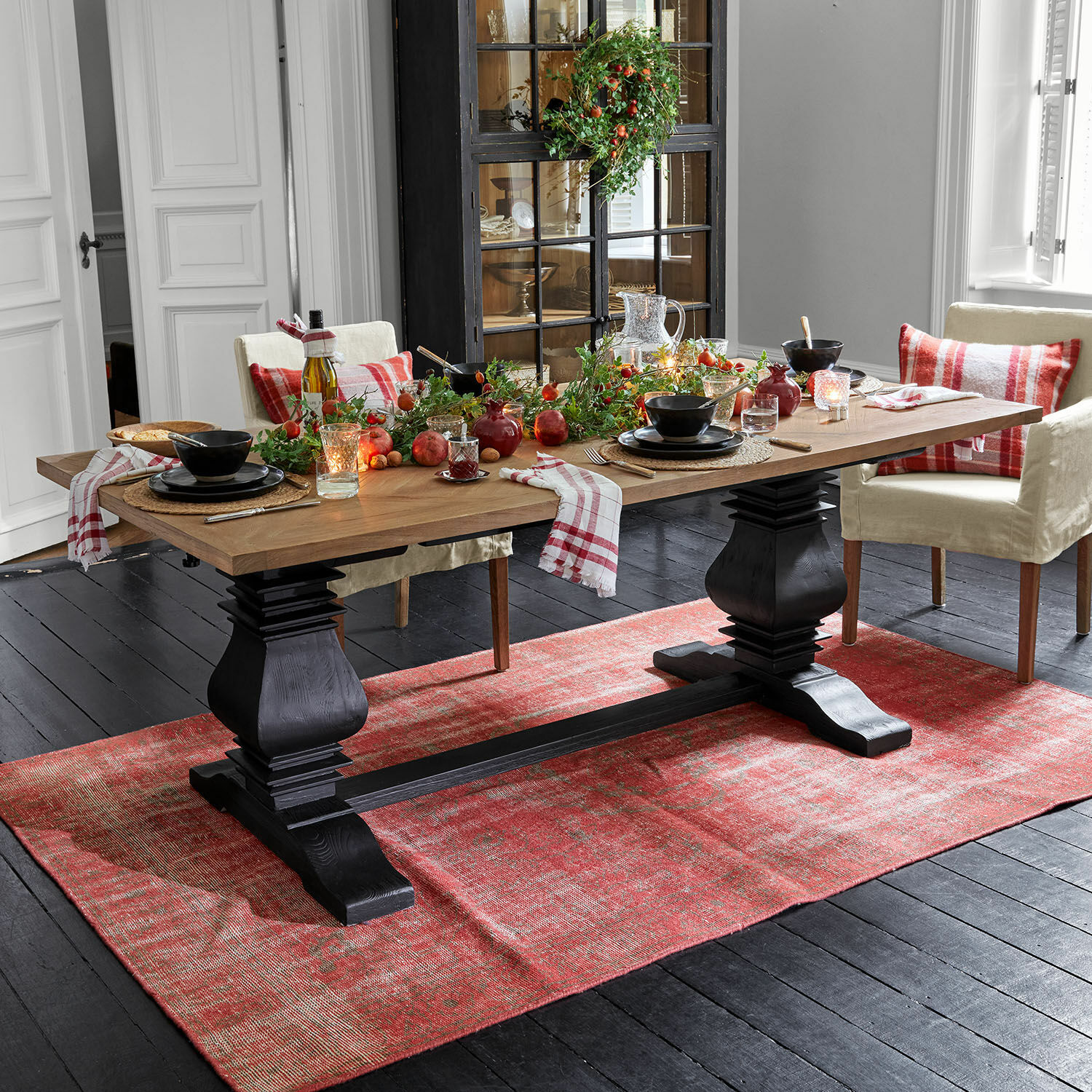 Table Quillancourt Table à manger en bois avec plateau naturel et pieds noirs sur tapis rouge, décorations festives