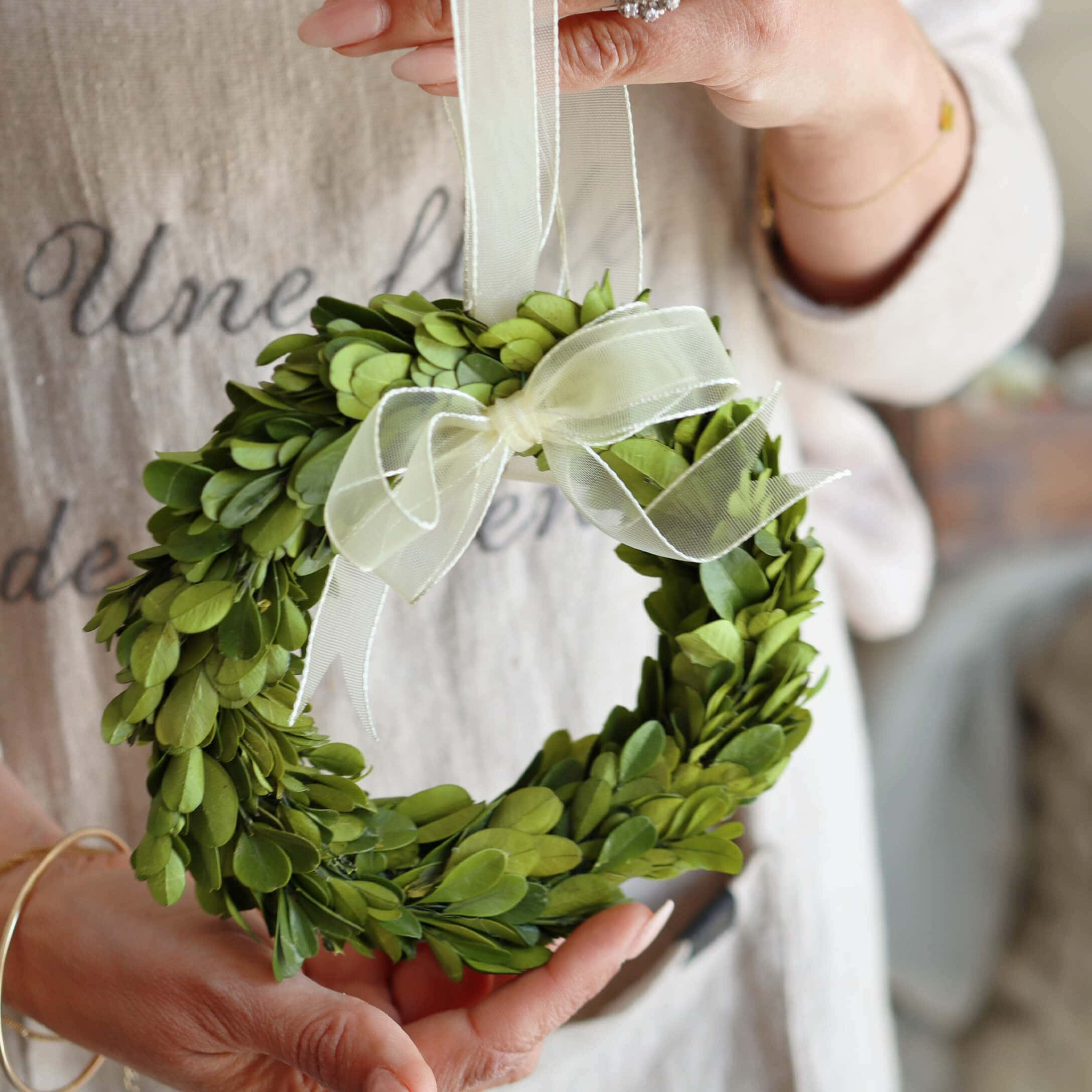 Petit couronne verte en feuilles avec un ruban blanc, décoration intérieure ou porte