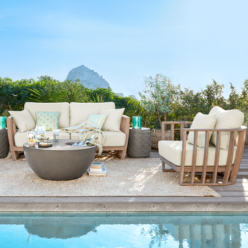 Ensemble de mobilier de jardin avec coussins beige et cadre en bois près de la piscine sur la terrasse