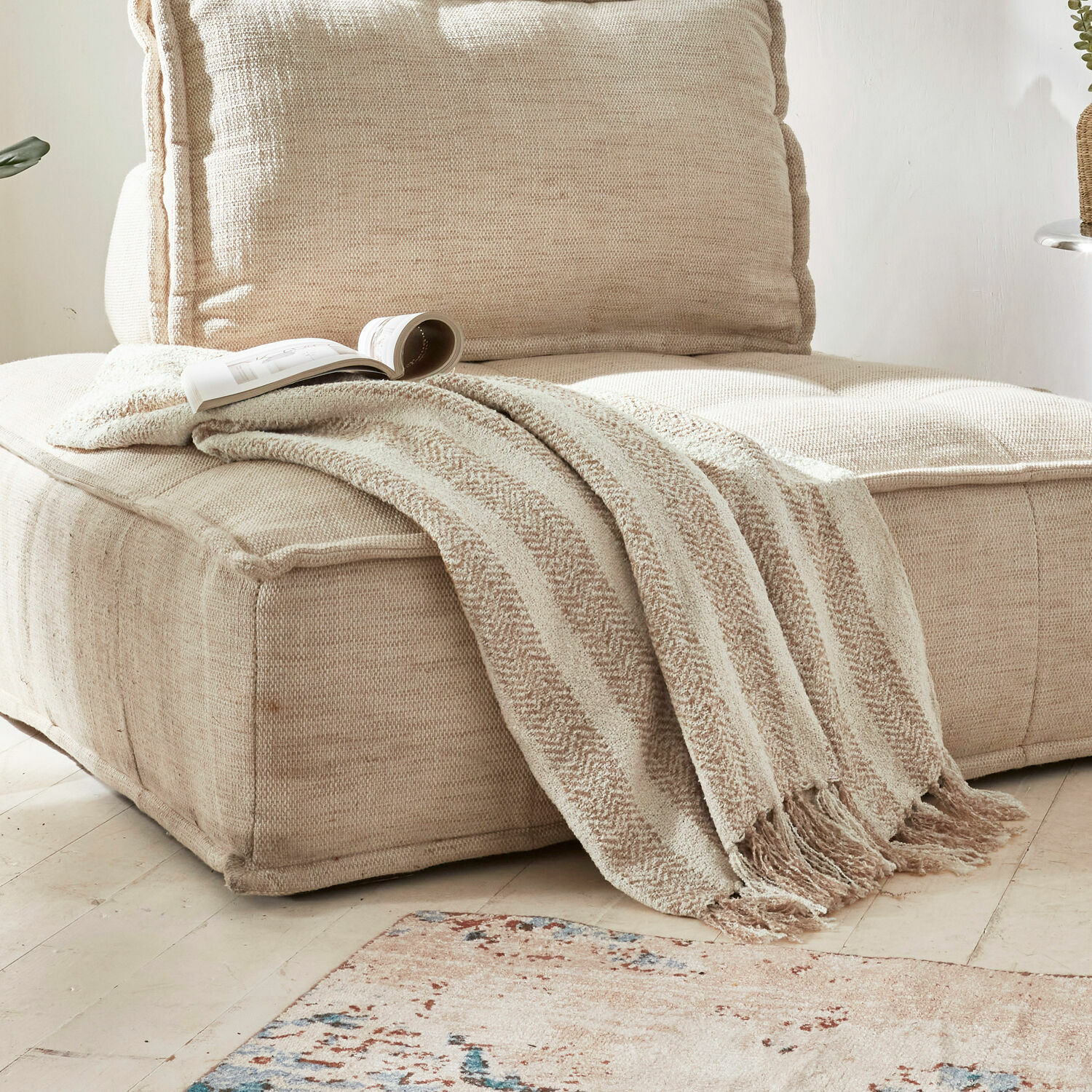 Plaid Aldan Plaid beige doux avec franges sur un canapé en tissu beige dans un salon lumineux