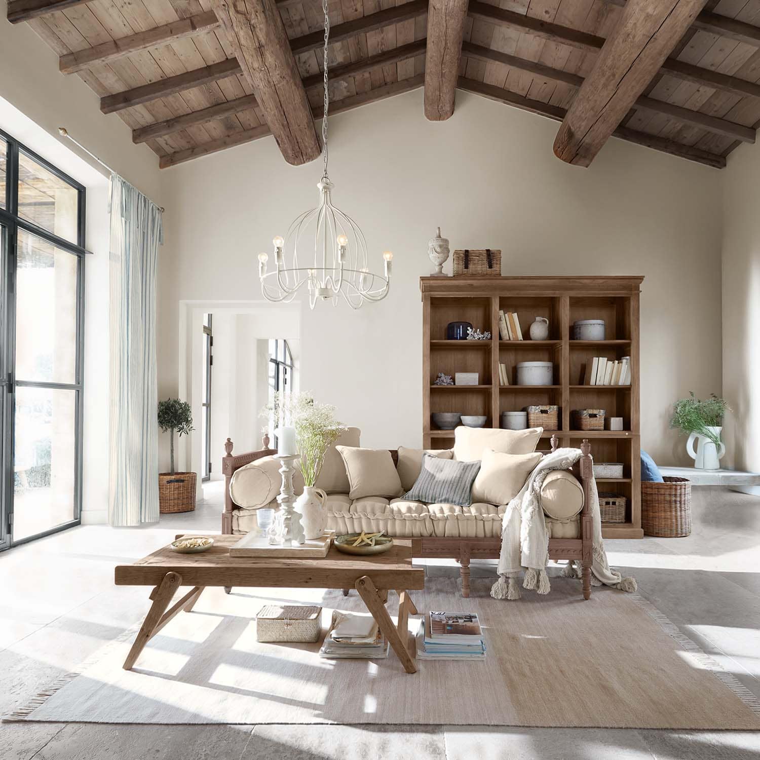 Salon chaleureux avec table en bois et canapé beige sous plafond en bois avec poutres apparentes