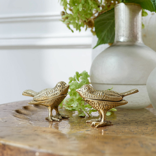 Deux figurines d'oiseaux décoratives en métal doré sur une table en bois, décoration intérieure