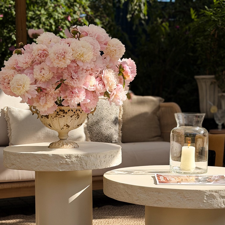 Bouquet décoratif de pivoines roses dans un vase en céramique sur une table claire en extérieur avec lumière naturelle