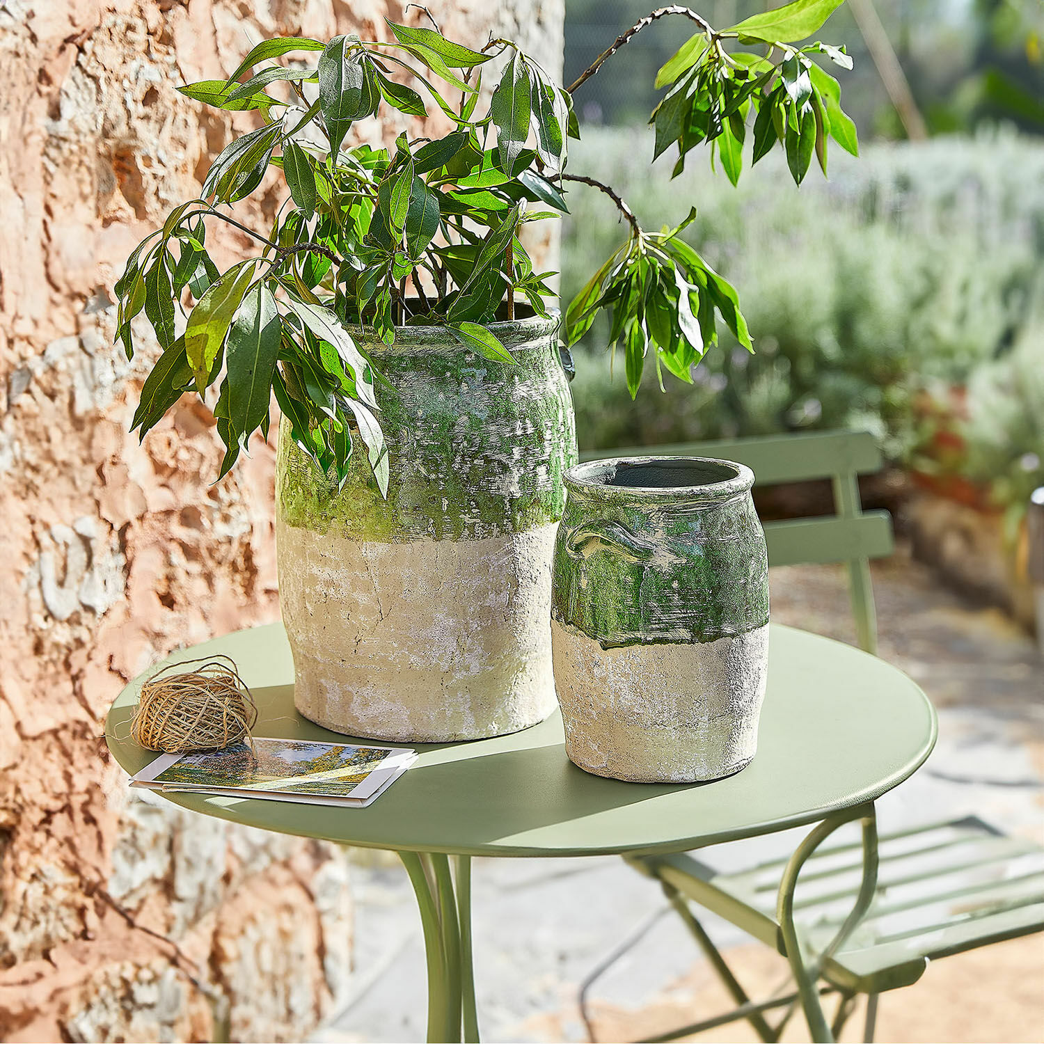 Lot de 2 vases Reefton Deux vases en céramique vert et beige sur une table de jardin verte avec plante décorative