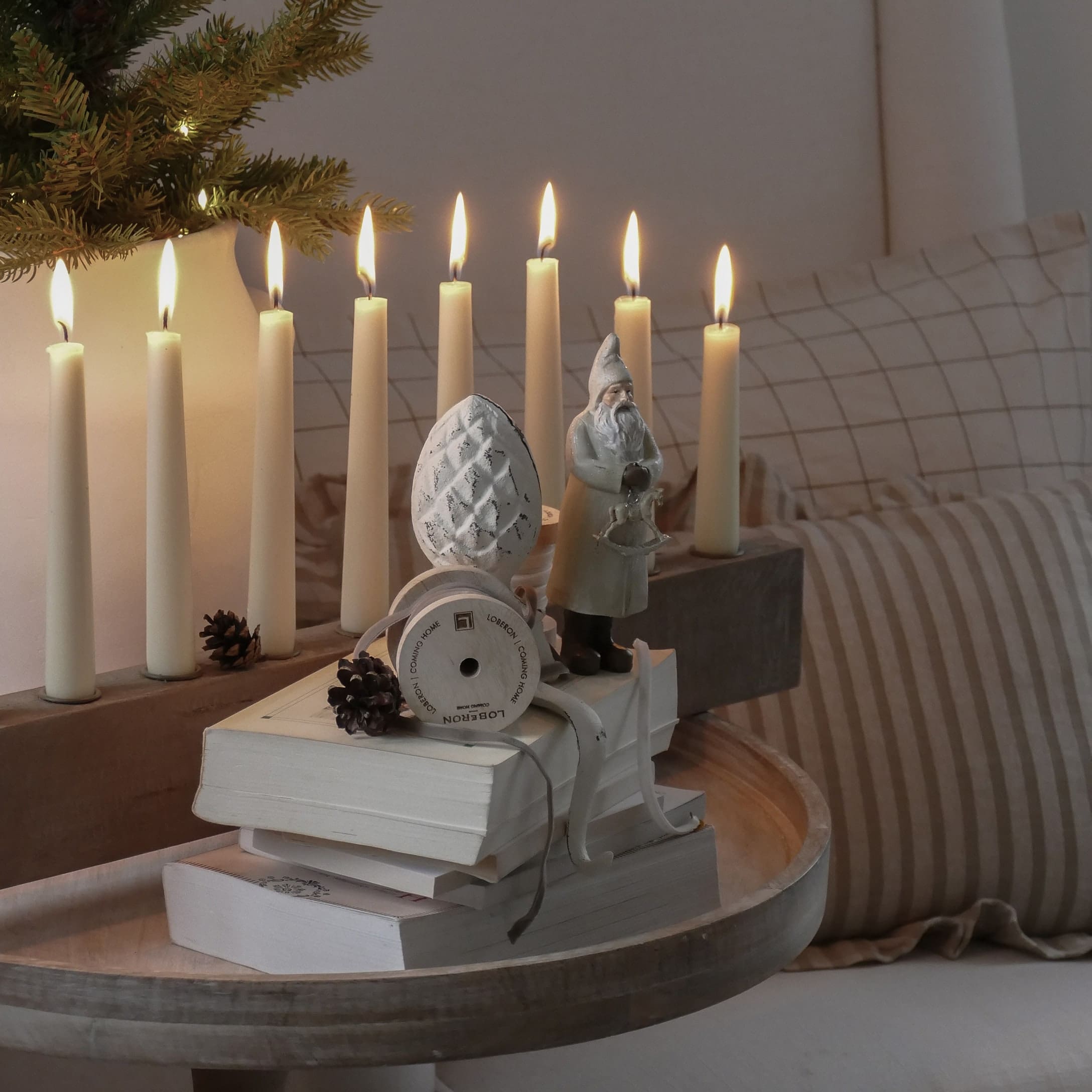 Décoration de Noël avec figurine de Père Noël, bougies allumées et livres sur plateau en bois clair