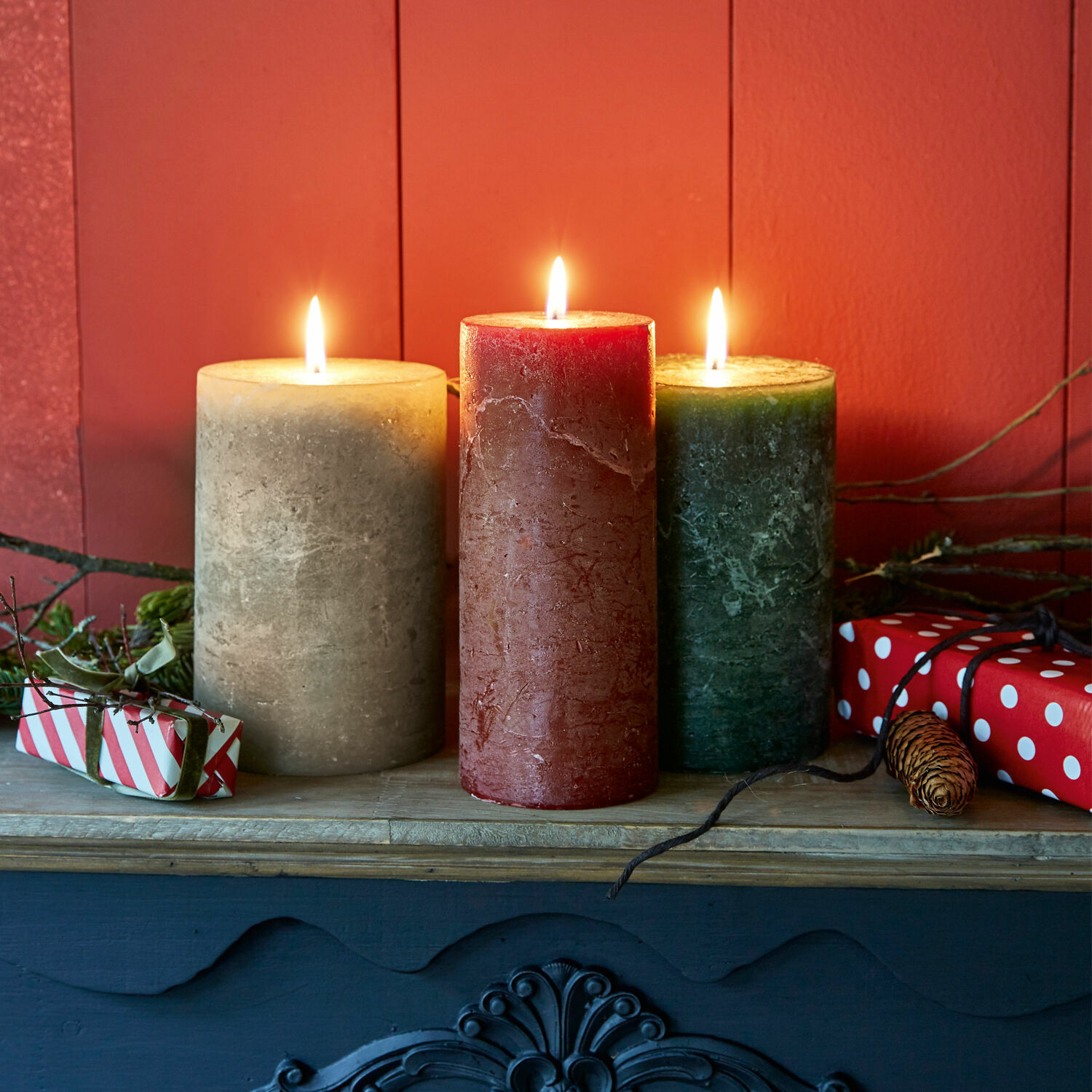 Lot de 3 bougies Salis Trois bougies en cire beige, rouge et verte sur une étagère en bois avec décorations de Noël