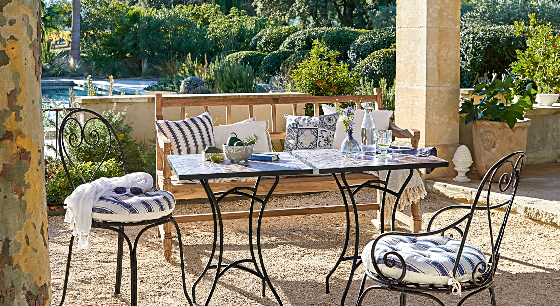 Ensemble de mobilier de jardin avec chaises en métal et banc en bois sur terrasse avec coussins rayés