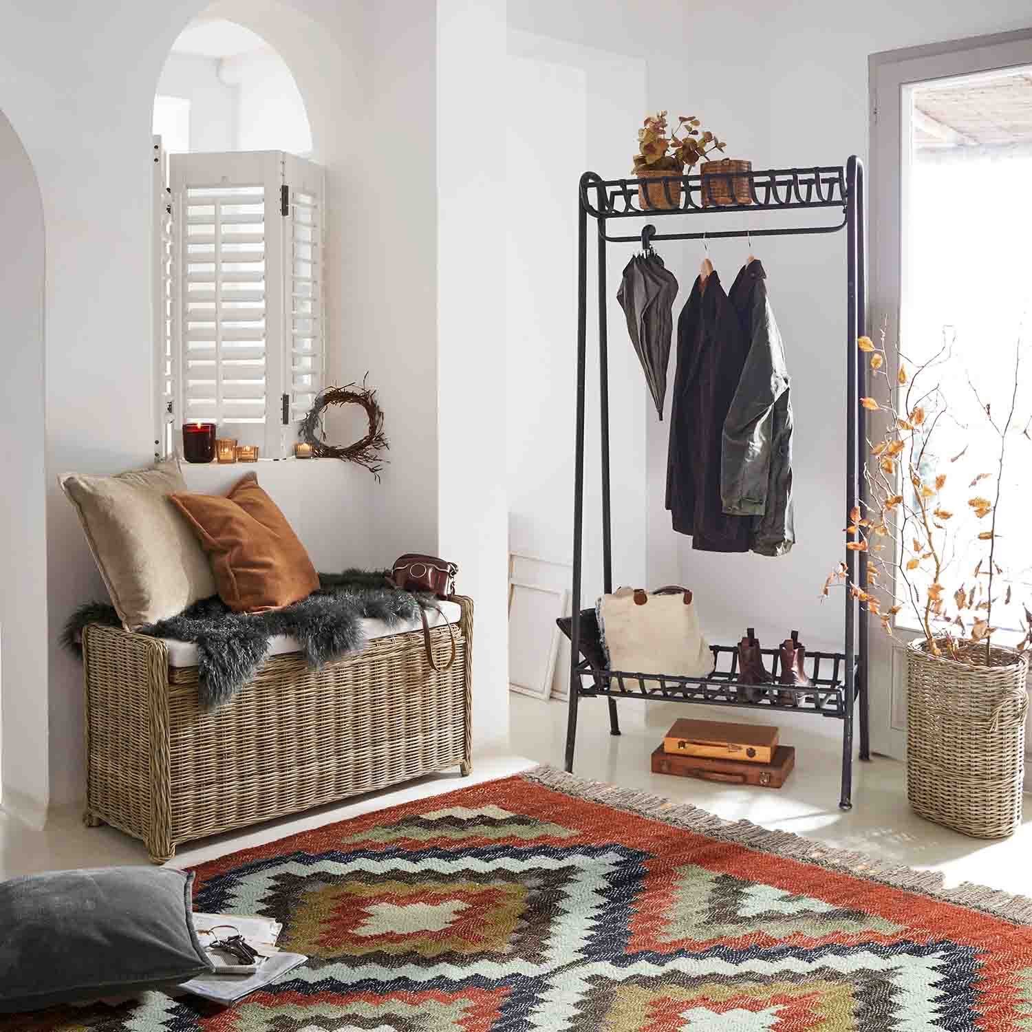 Entrée avec banc en osier, porte-manteau en métal noir et tapis coloré à motifs géométriques