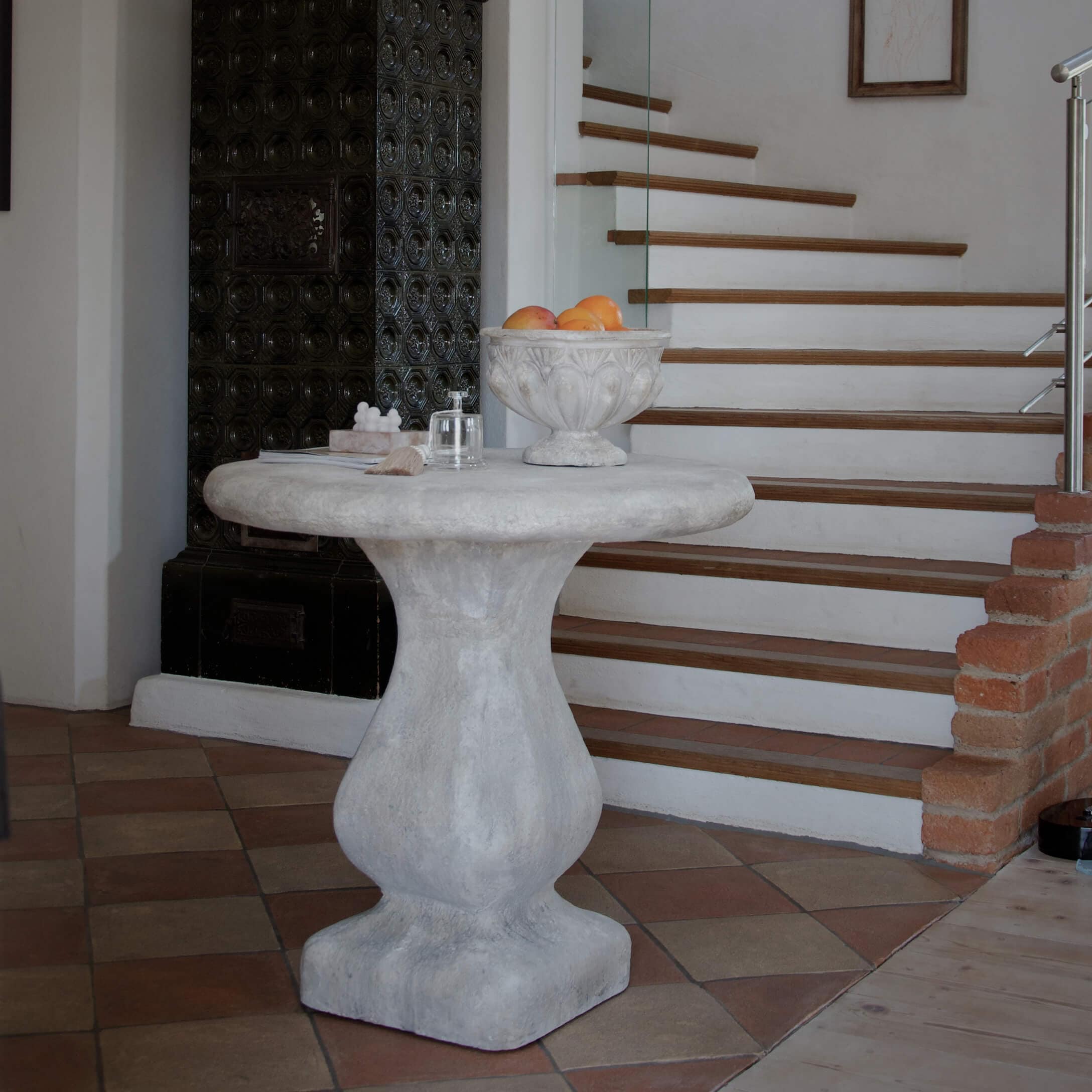 Table ronde en béton gris près d'un escalier, coupe décorative avec fruits sur le dessus