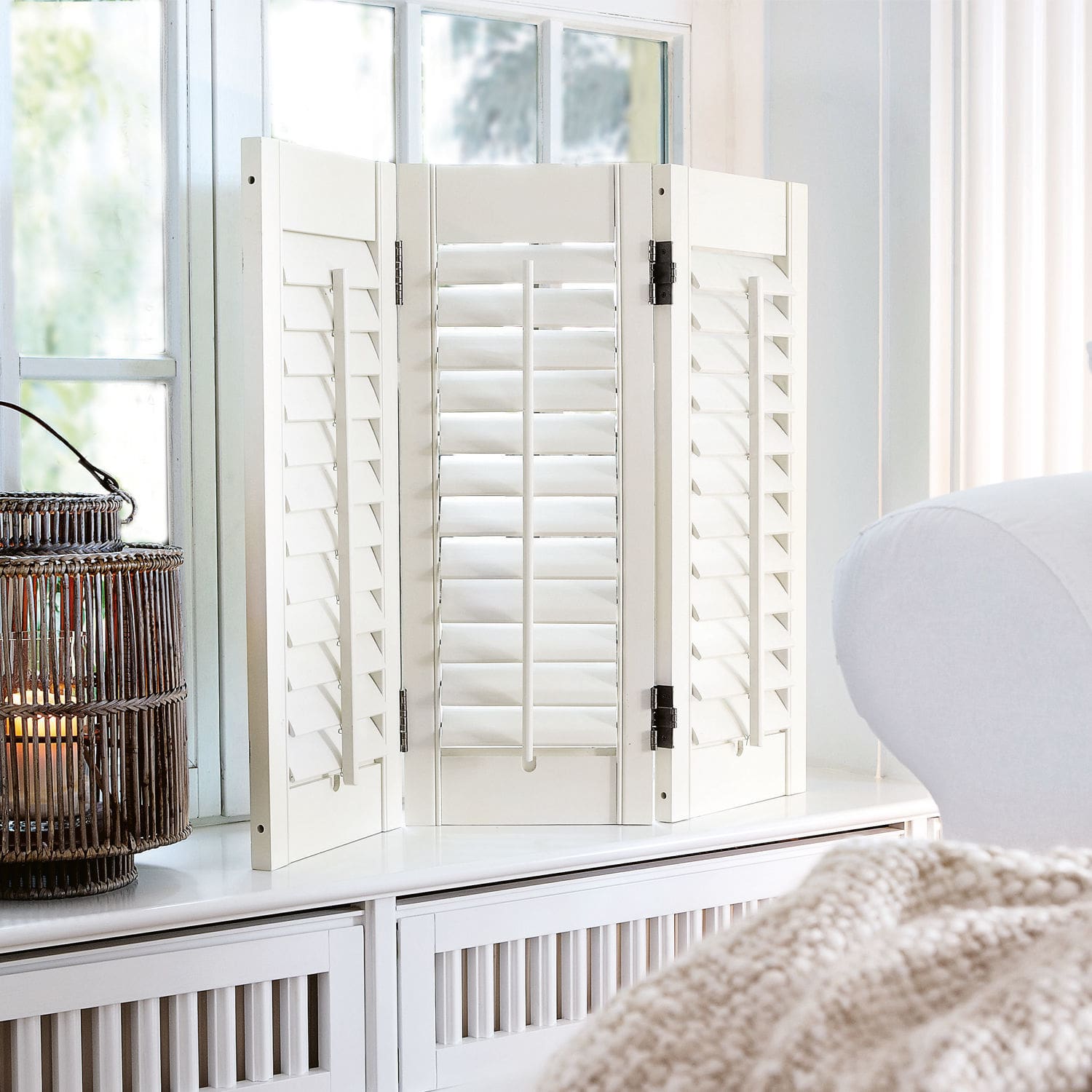 Paravent Ventura Paravent blanc en bois avec volets réglables posé sur un meuble dans un salon lumineux