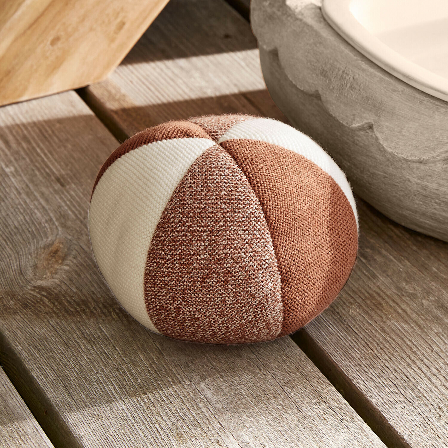 Jouet pour chien Wuffari Coussin rond en tissu rayé marron et blanc posé sur un sol en bois clair