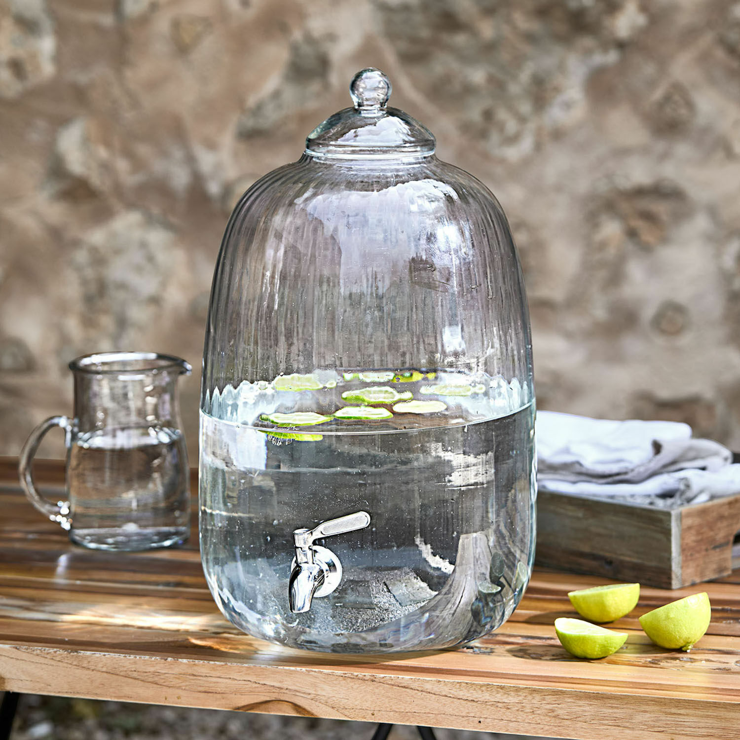 Distributeur de boisson Alindor Distributeur d'eau en verre transparent avec robinet et couvercle, tranches de citron vert flottantes sur table