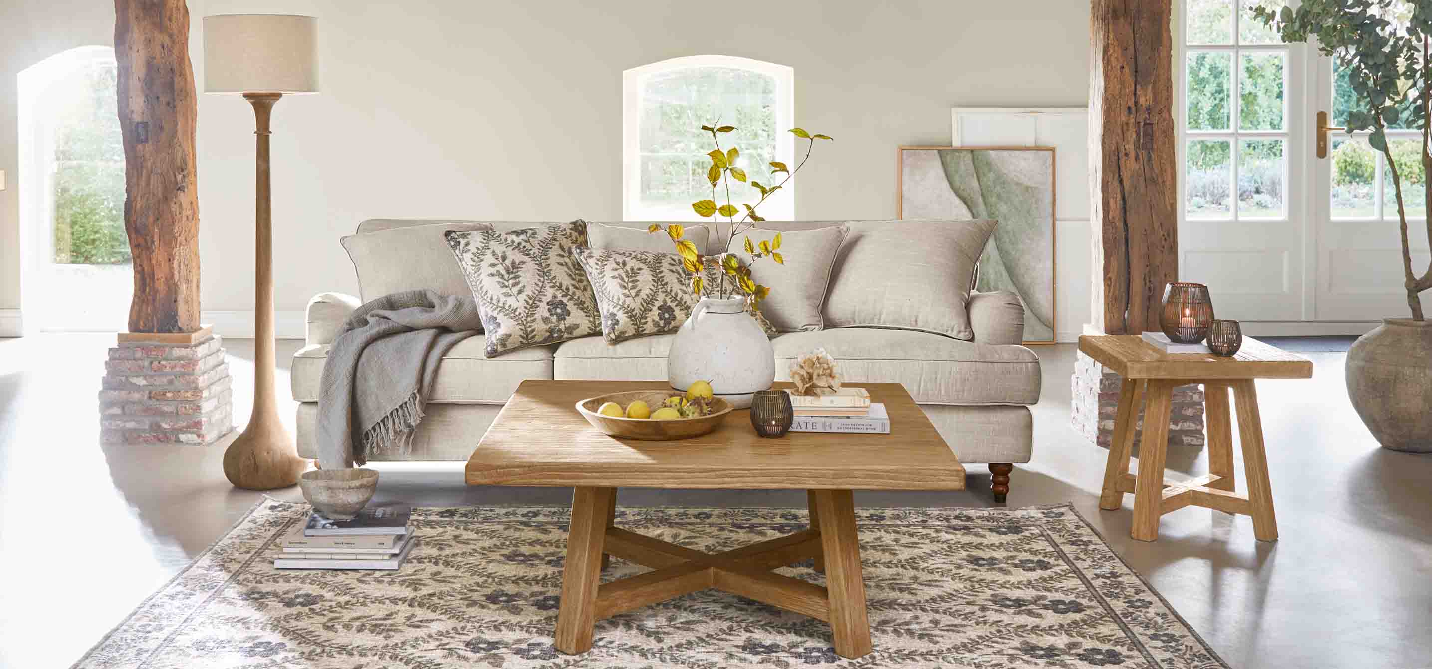 Salon chaleureux avec canapé beige, table basse en bois et lampe sur pied dans des tons naturels