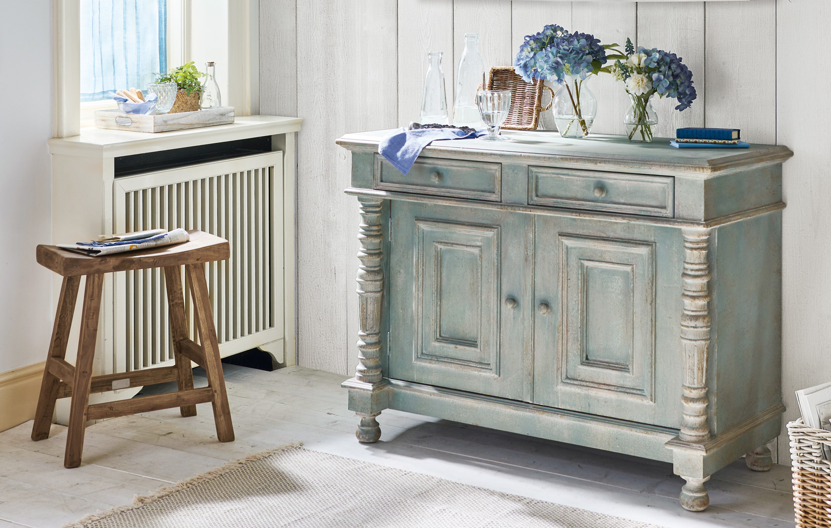 Buffet shabby chic en bois vert-gris avec fleurs décoratives et verres sur le dessus