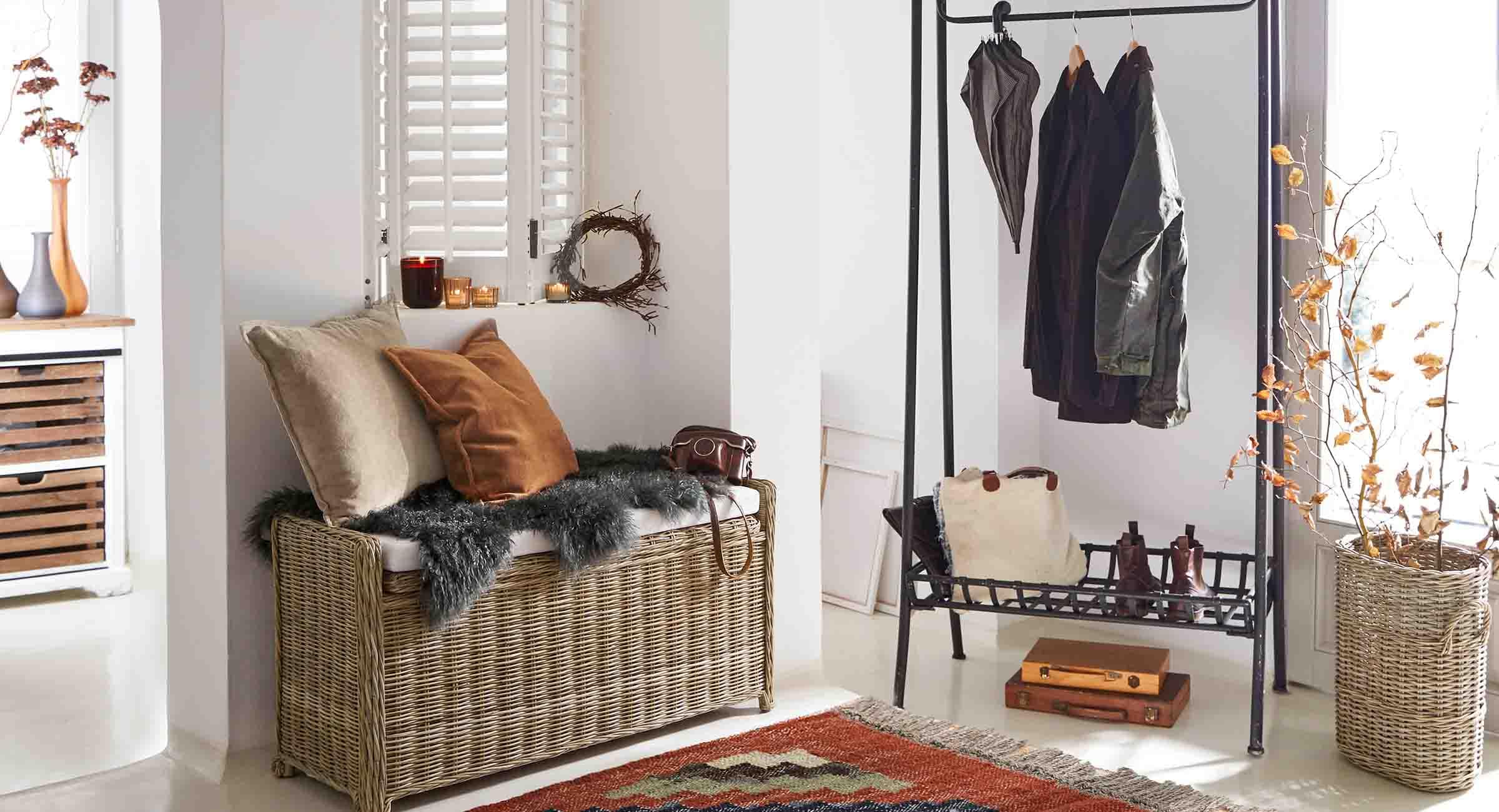 Entrée avec banc en osier, porte-manteau en métal noir et décorations aux tons naturels et clairs