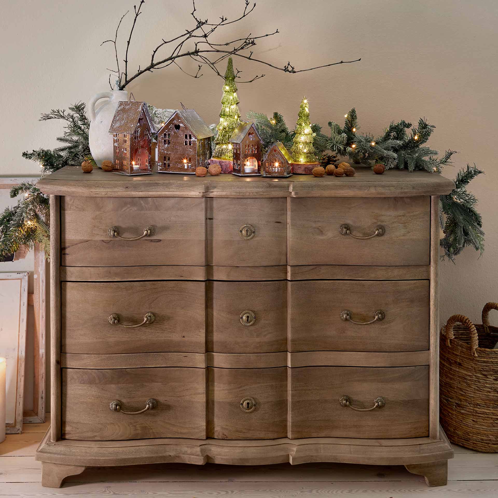 Décoration de Noël avec lanternes en métal en forme de maisons et sapins verts lumineux sur commode en bois
