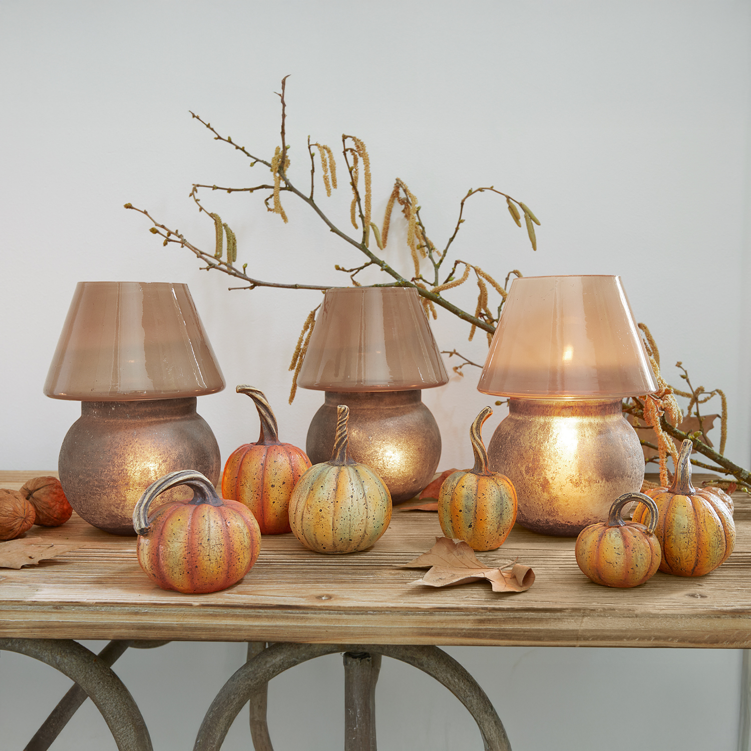 Lanterne décorative en verre cuivré avec citrouilles décoratives sur une table en bois