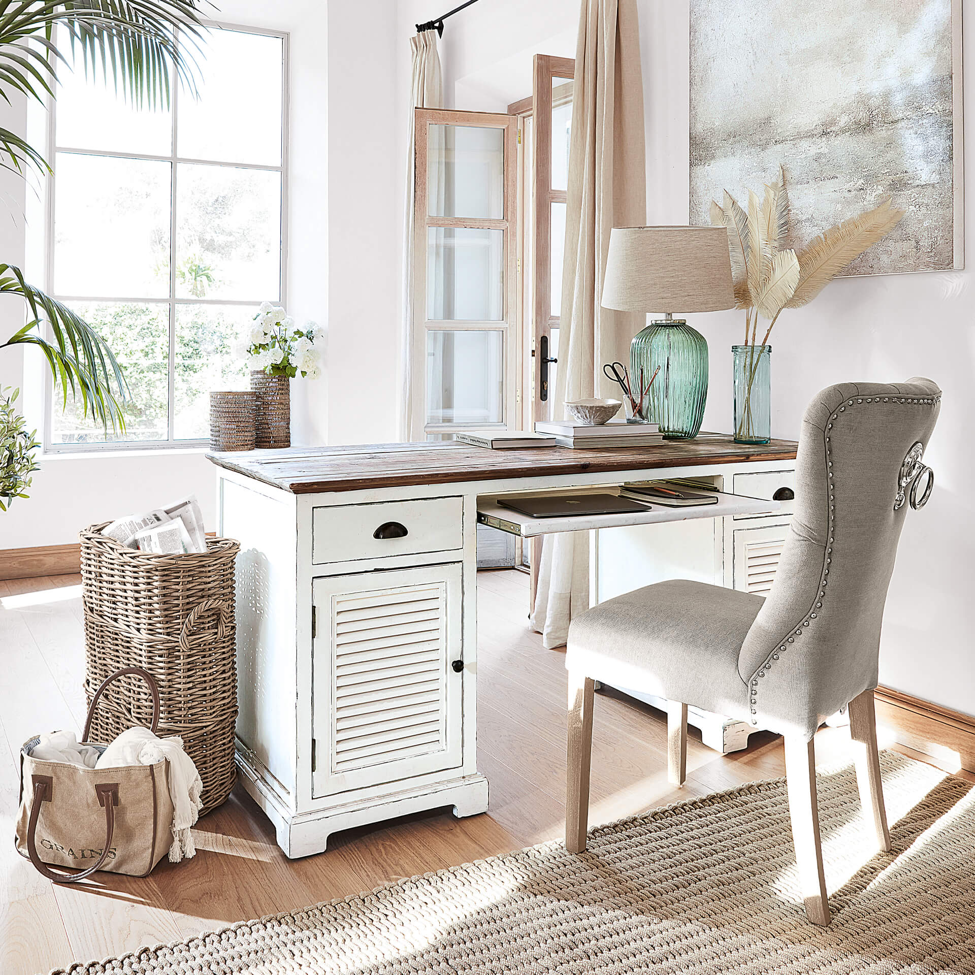 Bureau en bois blanc avec tiroirs et chaise rembourrée grise dans une pièce lumineuse et accueillante