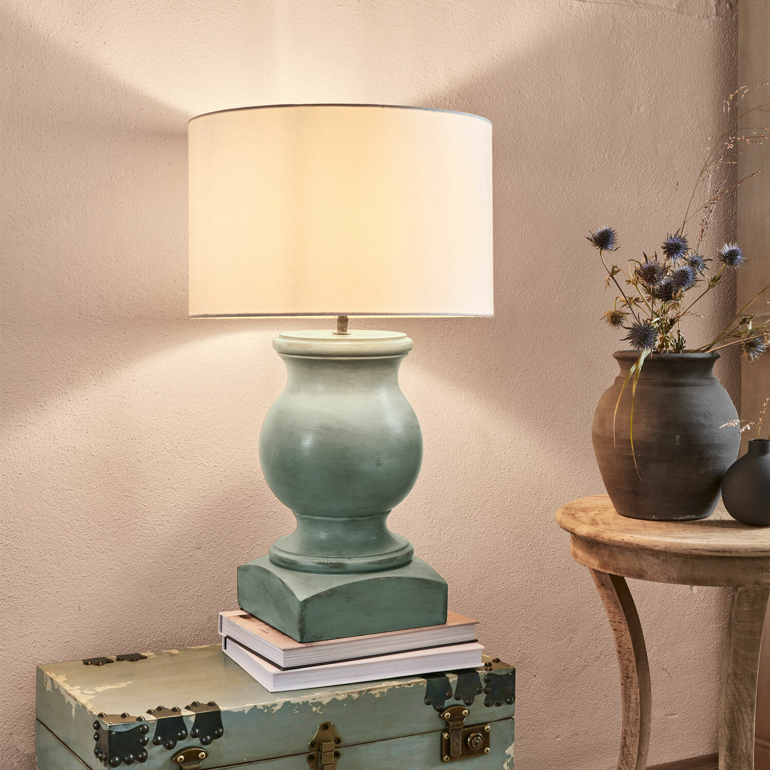 Lampe à poser Todd Lampe de table en céramique verte avec abat-jour beige posée sur un coffre ancien, décoration intérieure