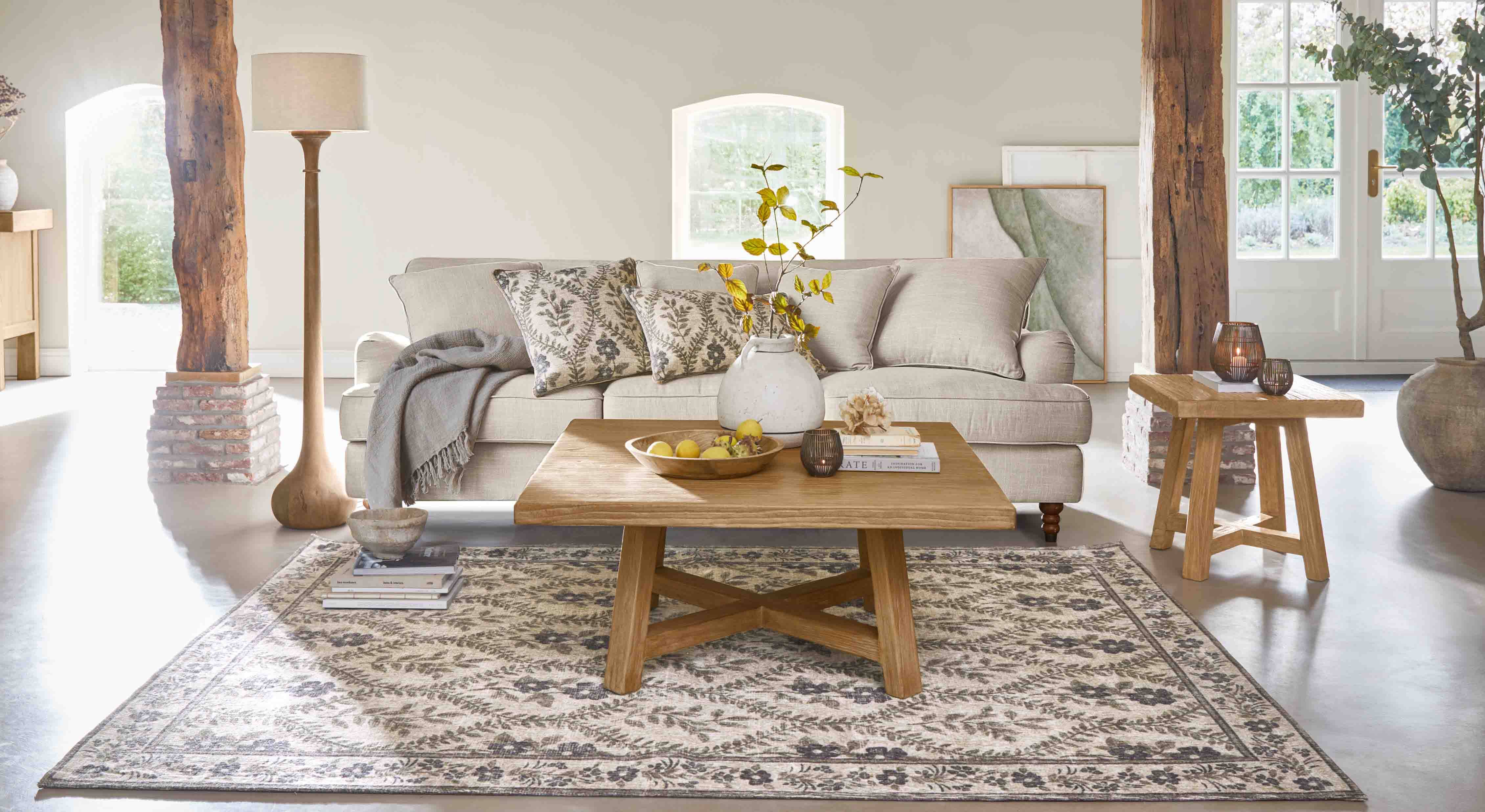 Salon chaleureux avec canapé beige, table basse en bois et tapis décoratif à motif floral