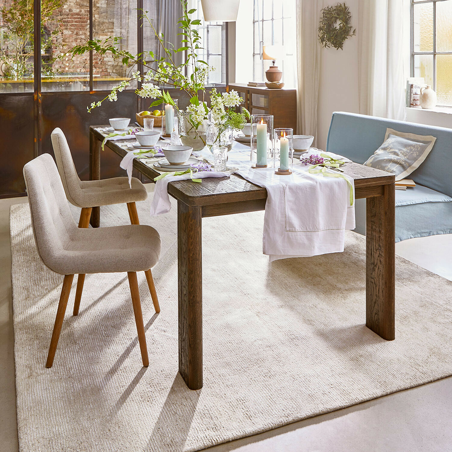 Table Gianoro Table à manger rustique en bois foncé avec chemin de table blanc et bougies dans un salon lumineux