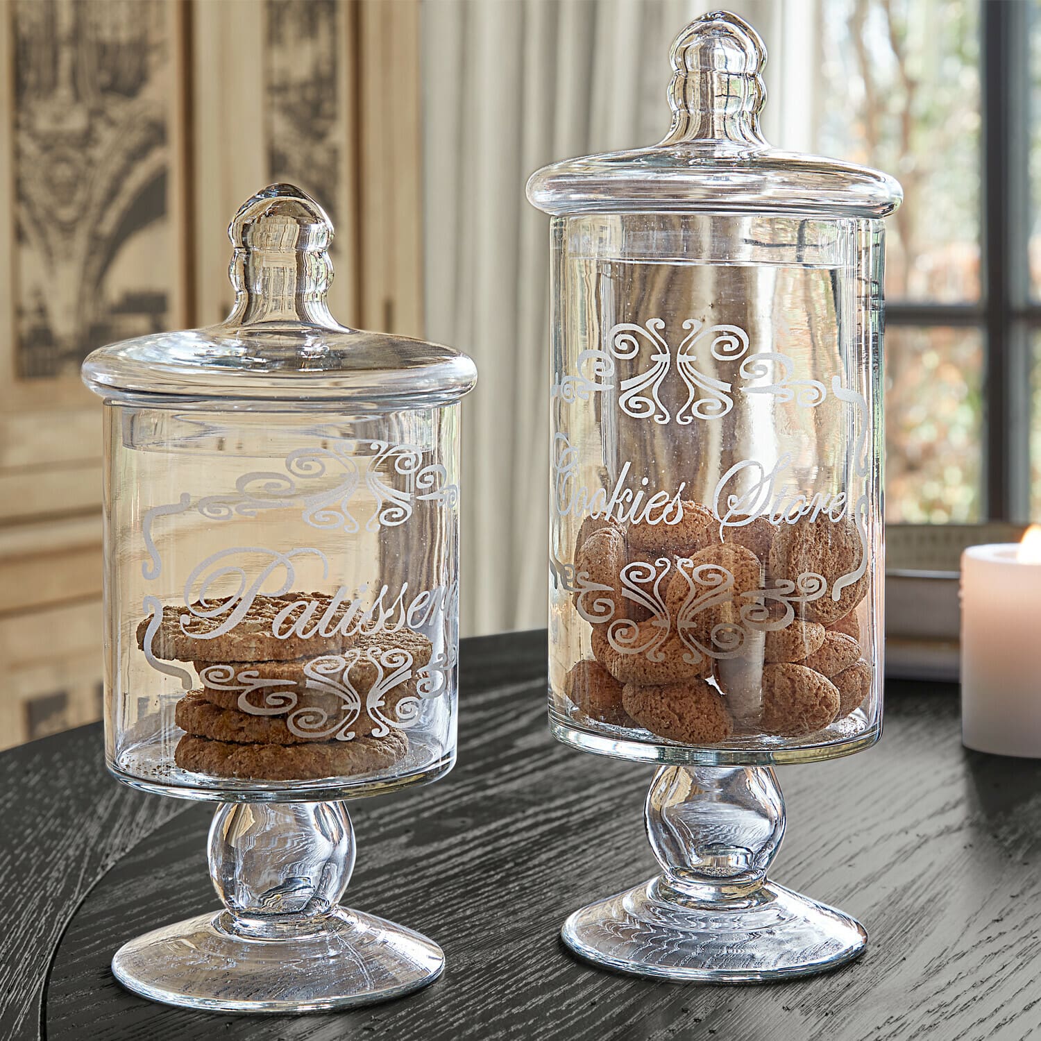 Bocaux en verre avec couvercles et inscriptions décoratives remplis de biscuits sur une table noire