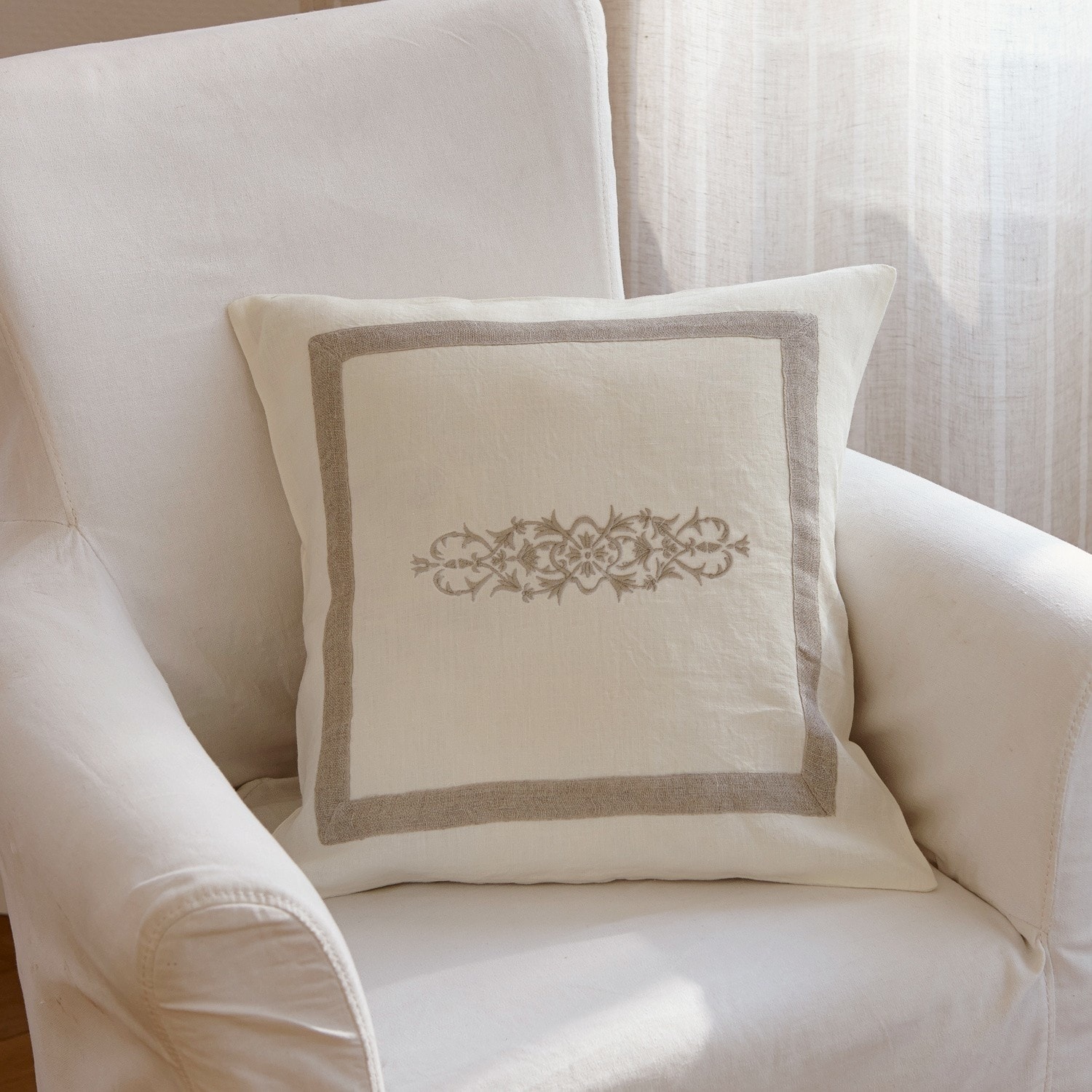 Housse de coussin Eppeville Coussin décoratif en lin beige avec motif brodé et bordure sur fauteuil crème