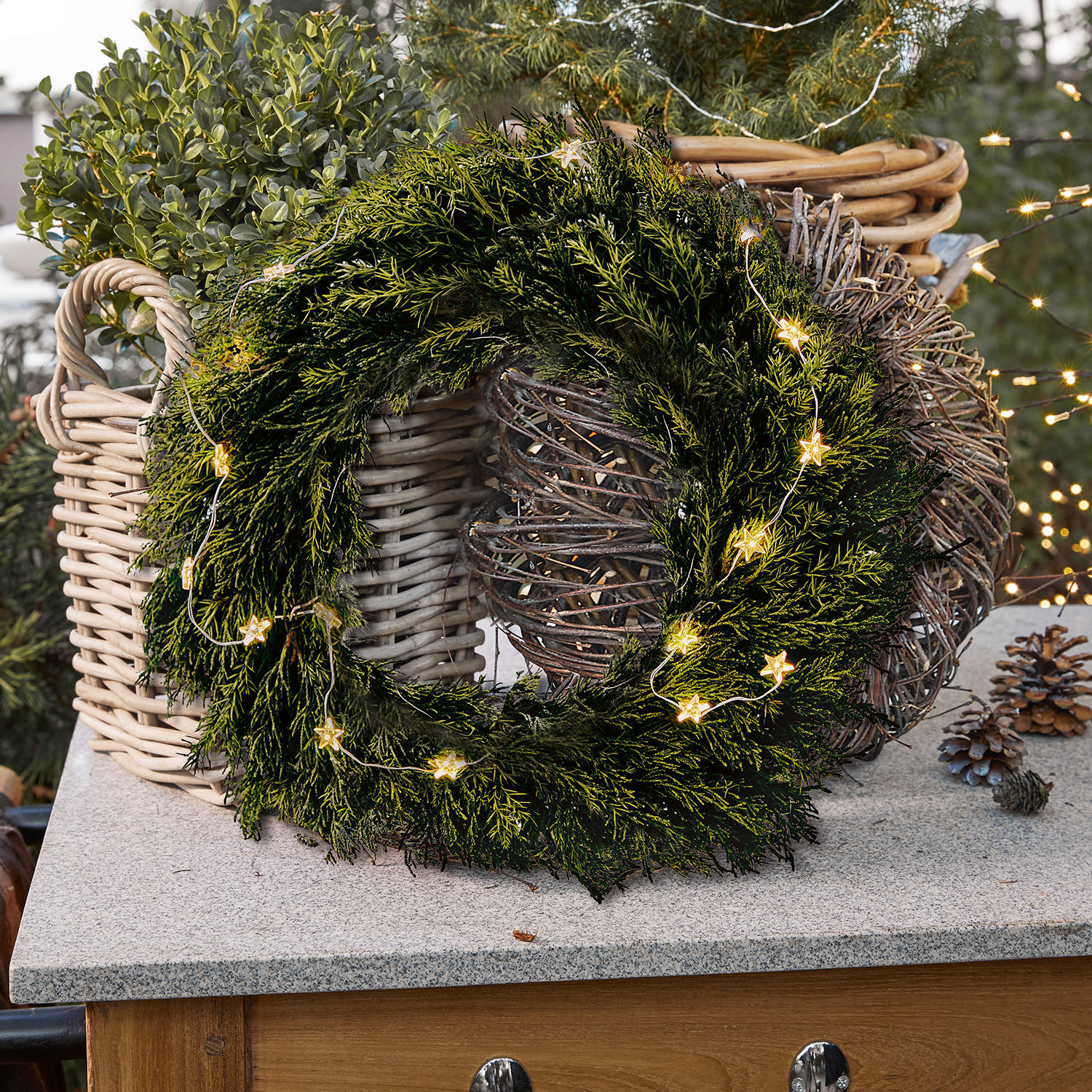 Couronne Évres Couronne de Noël verte en branches avec guirlande lumineuse en forme d'étoiles sur un comptoir en pierre