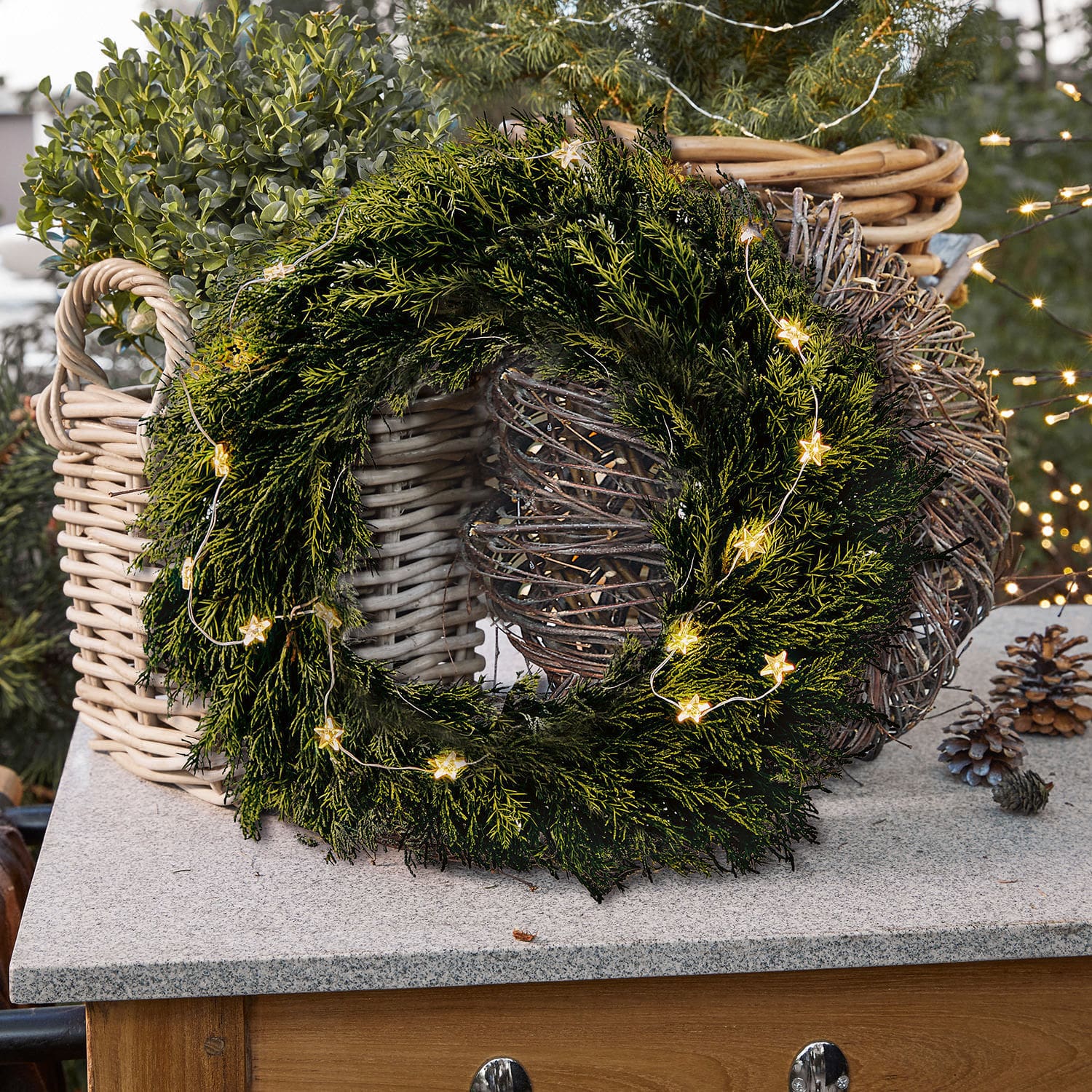 Couronne Évres Couronne de Noël verte en branches avec guirlande lumineuse en forme d'étoiles sur un comptoir en pierre