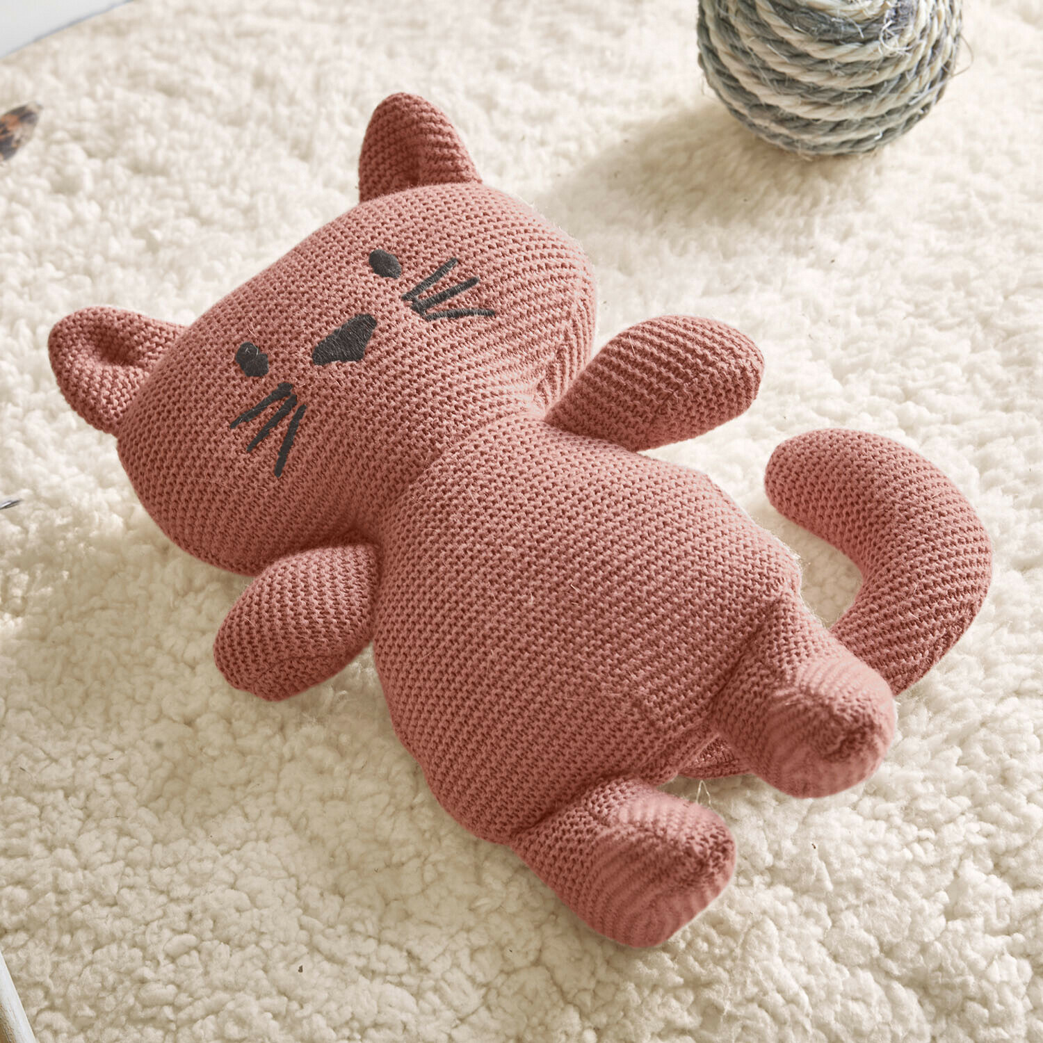 Chat en peluche tricoté rose en coton sur tapis blanc moelleux, jouet pour enfant doux