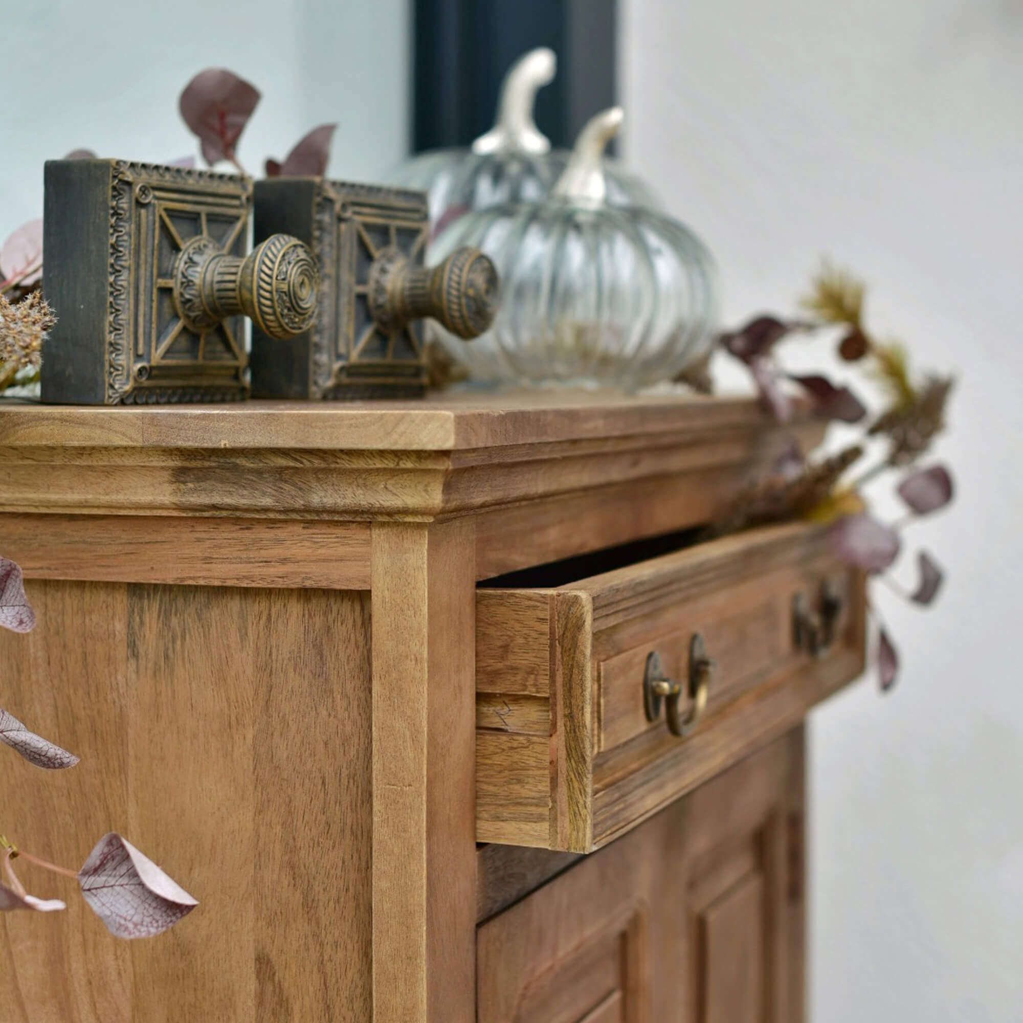 Commode en bois avec tiroir ouvert, poignées en laiton décoratives et décorations en verre en forme de citrouille