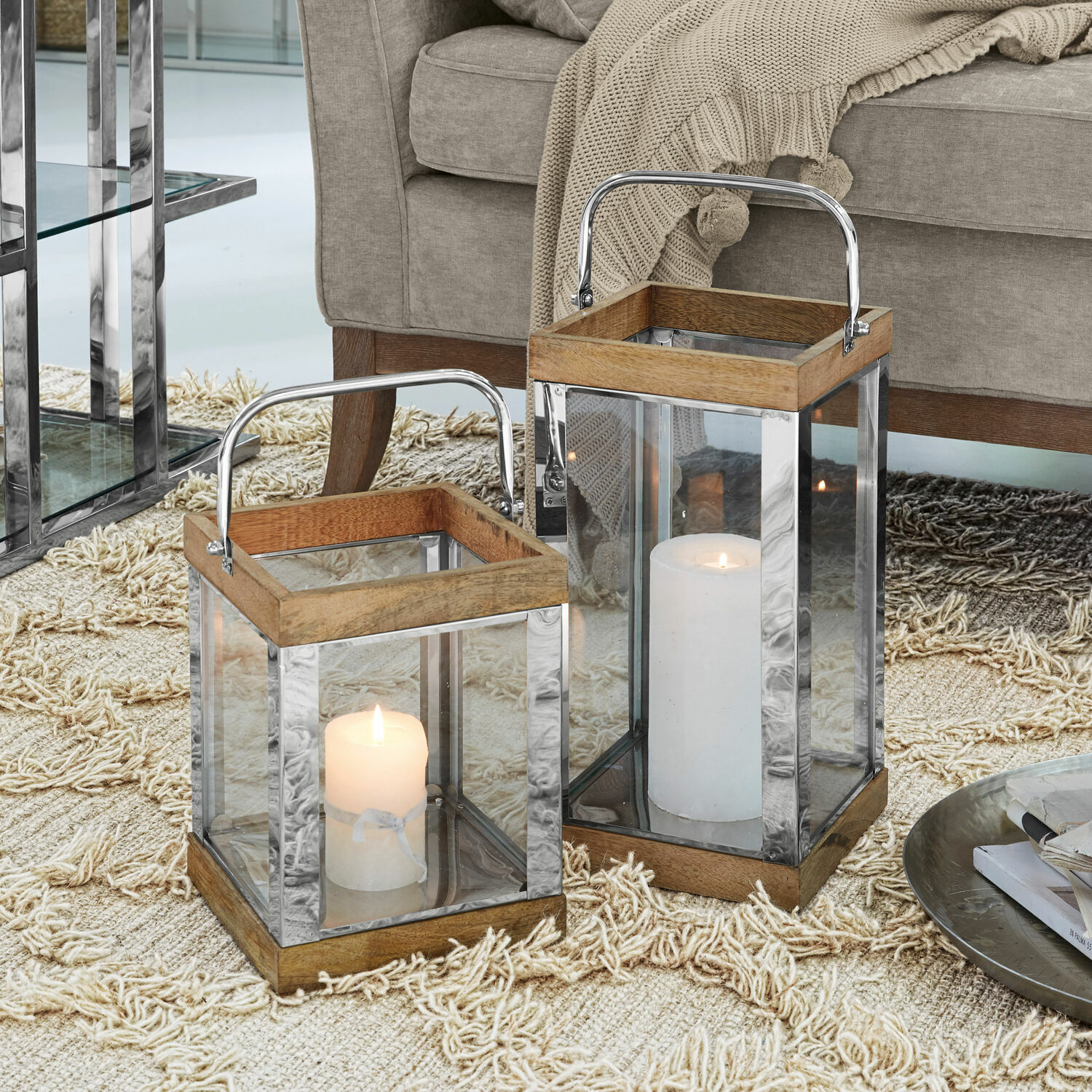 Lot de 2 lanternes Harpers Deux lanternes en bois et métal avec parois en verre et bougies blanches sur tapis beige