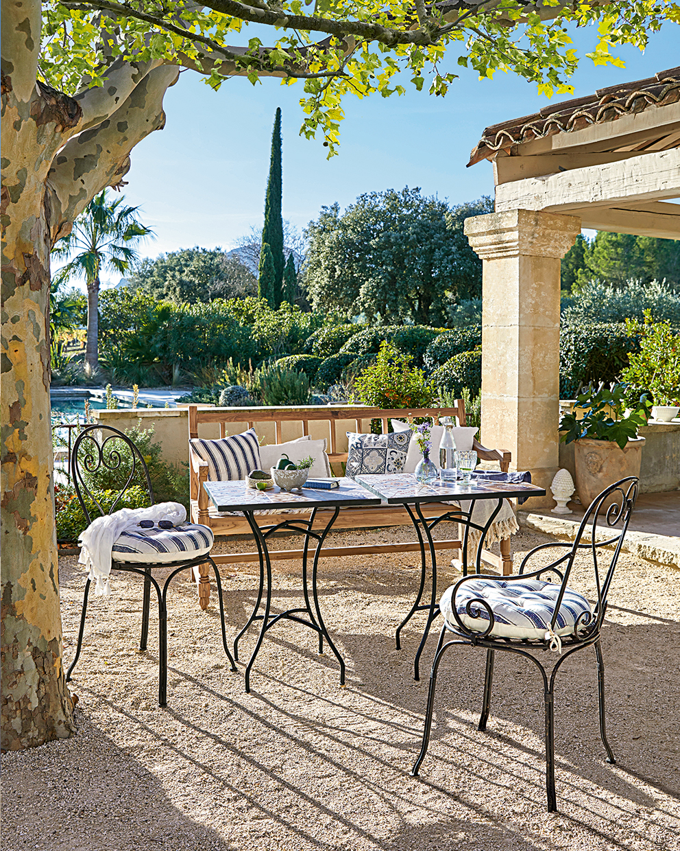 Ensemble de mobilier de jardin avec chaises en métal et banc en bois sur terrasse ensoleillée