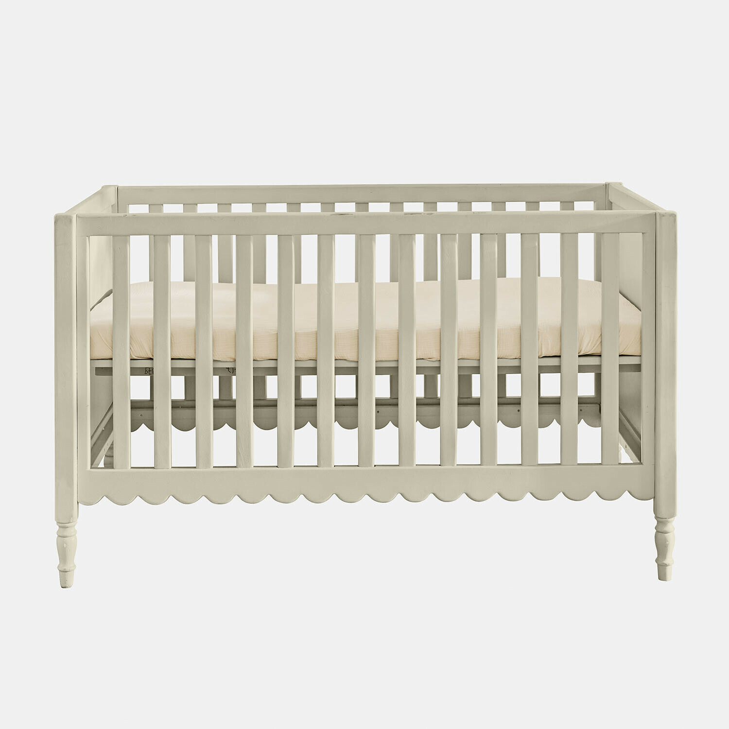 Lit bébé Leily Lit bébé en bois blanc avec matelas beige et bordure décorative festonnée en bas