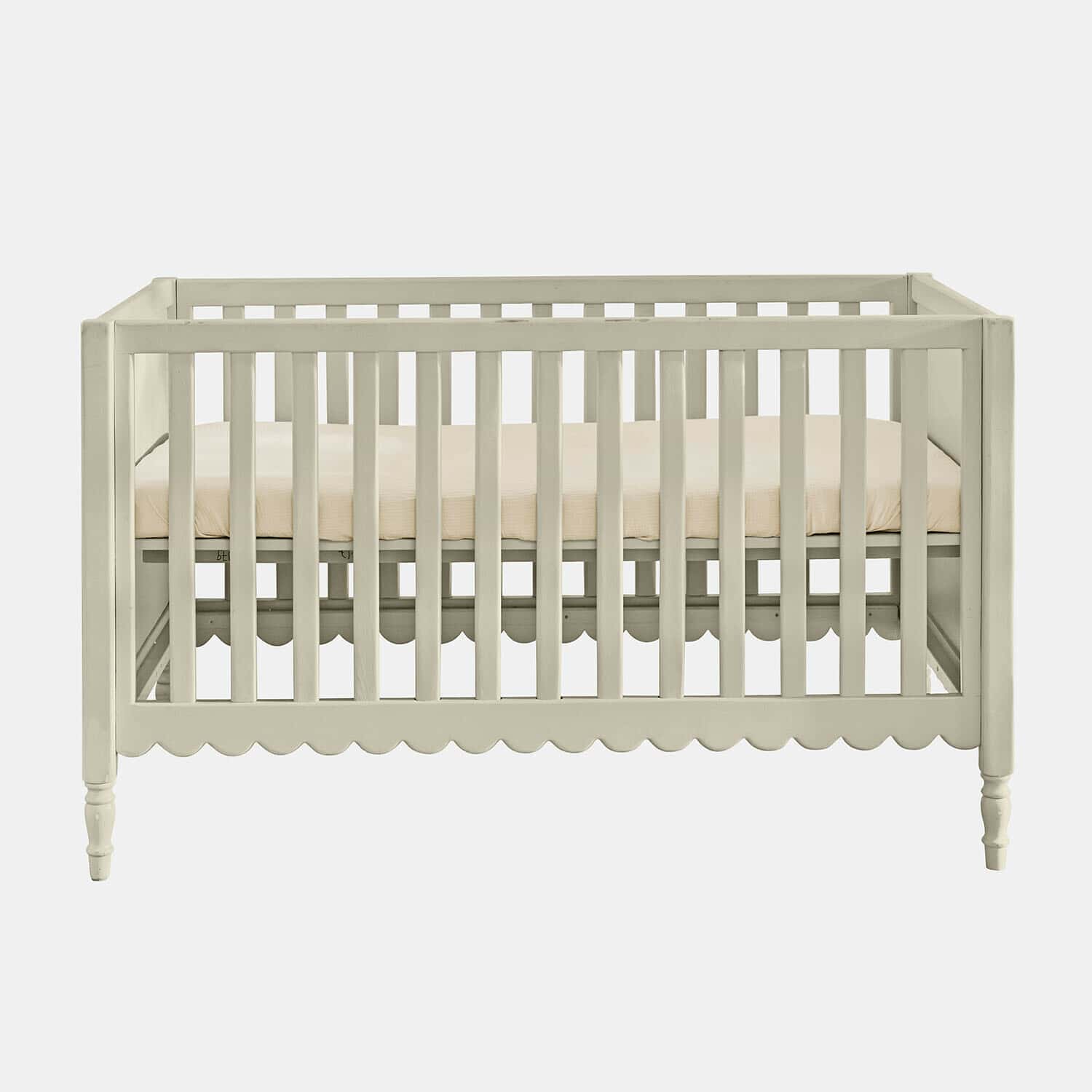 Lit bébé Leily Lit bébé en bois blanc avec matelas beige et bordure décorative festonnée en bas