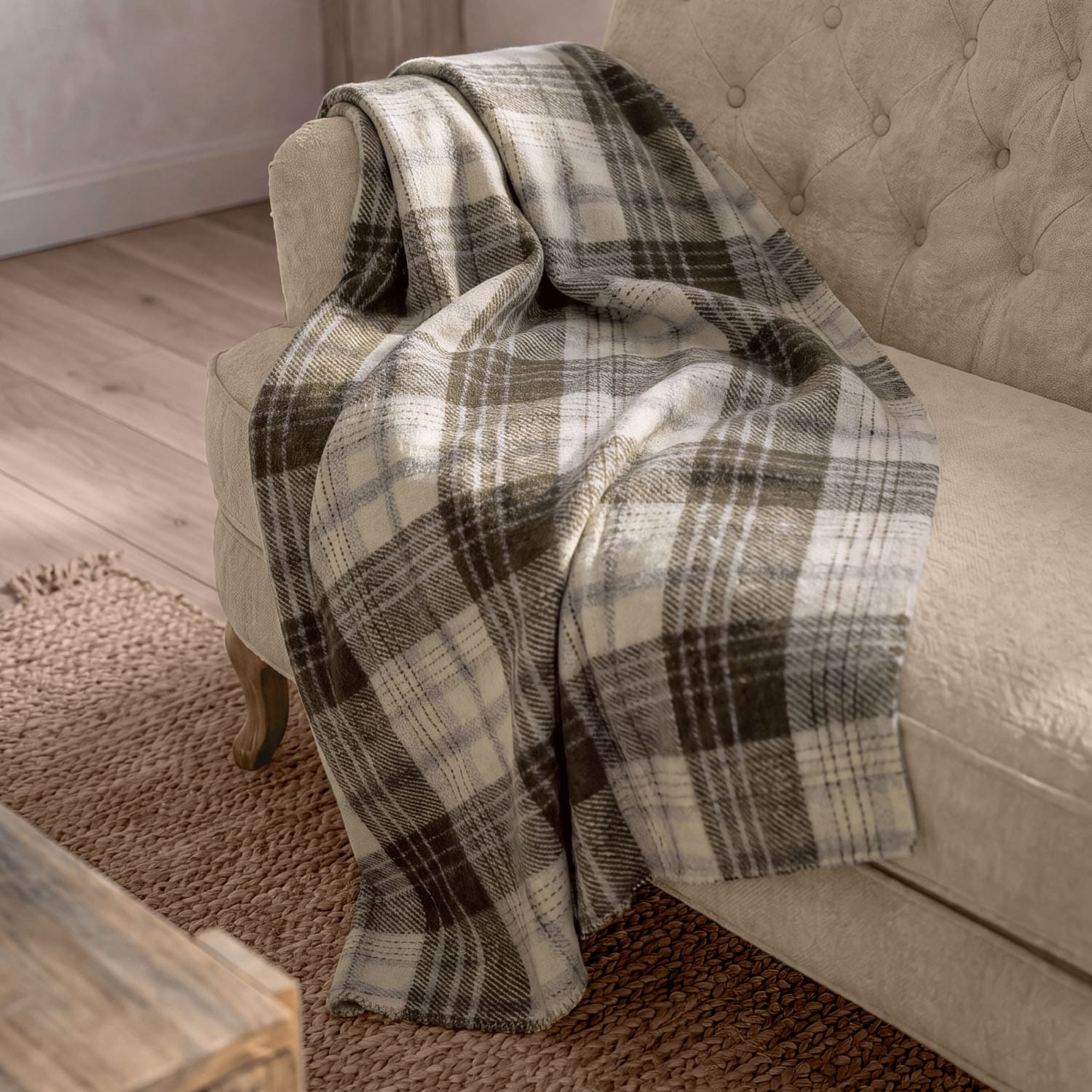 Plaid doux à carreaux beige et marron posé sur un canapé beige dans un salon cosy