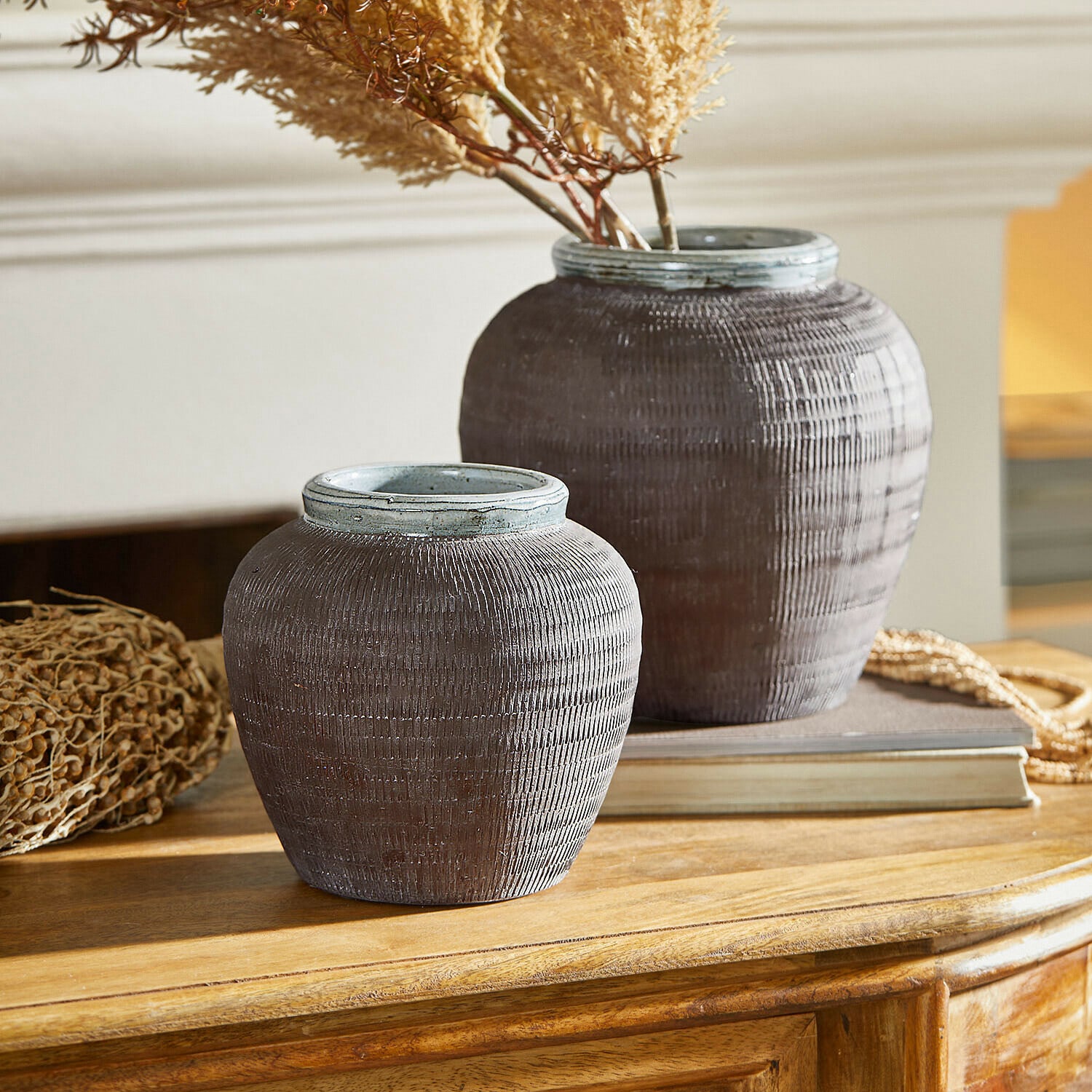 Lot de 2 vases Calverna Deux vases décoratifs en céramique marron posés sur une table en bois avec des plantes séchées