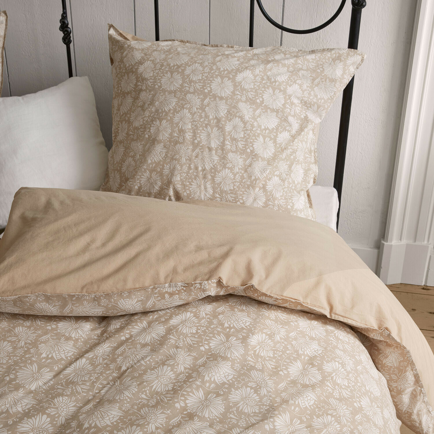 Parure de lit Jouvenay Parure de lit beige en coton avec motif floral blanc sur un lit à cadre métallique noir