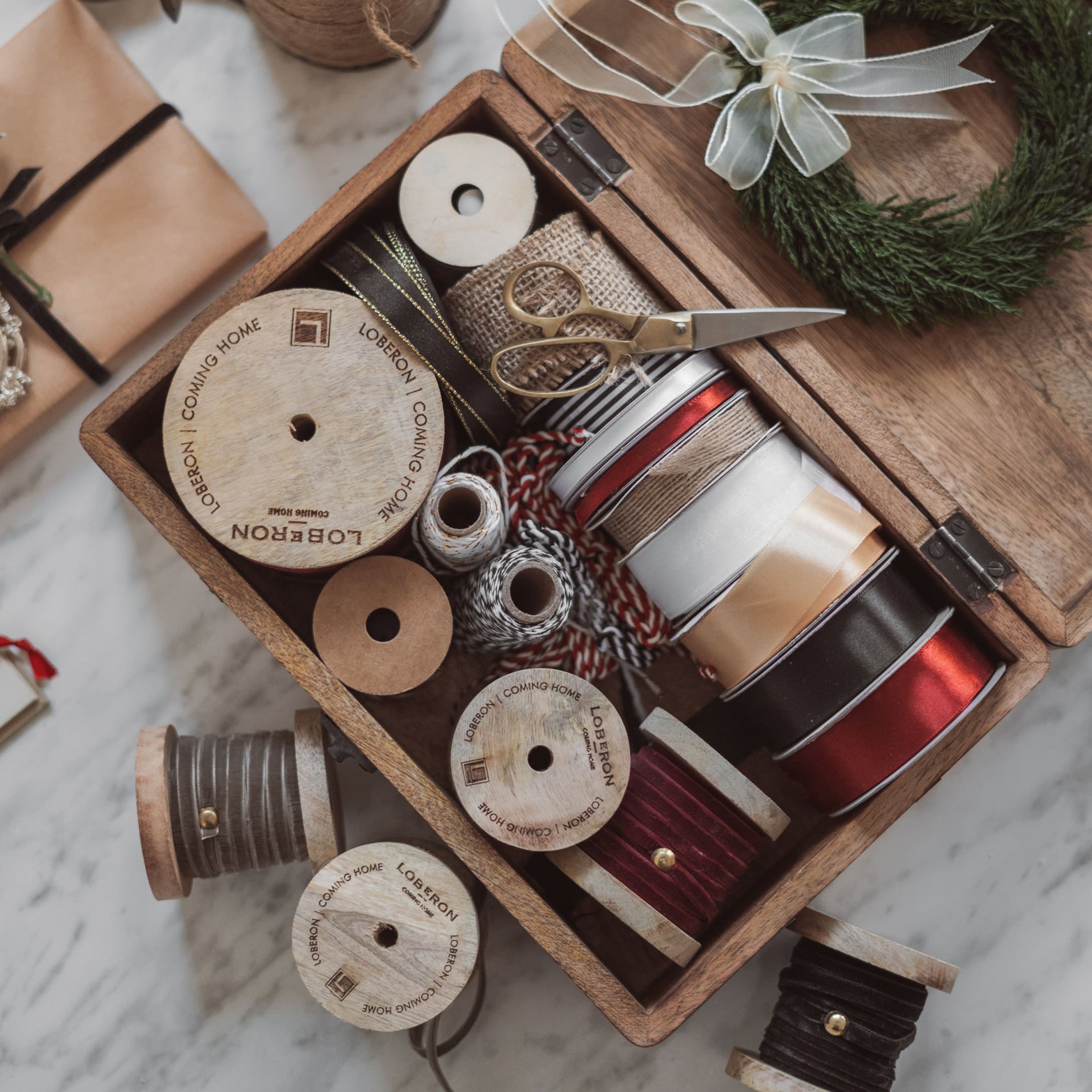 Bobines en bois avec rubans variés et ciseaux dans une boîte pour décoration et emballage cadeau
