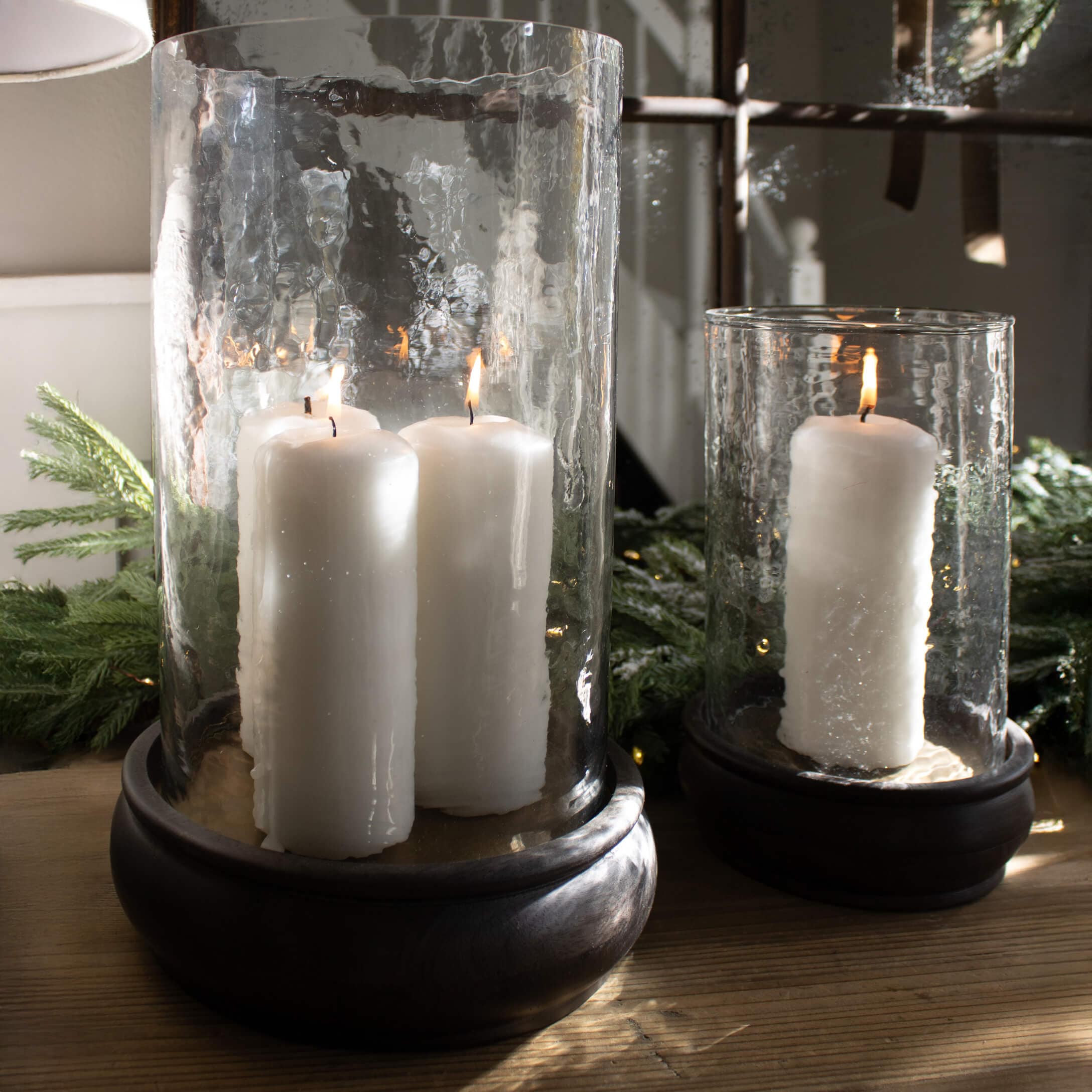 Lanterne en verre avec bougies blanches sur socle en bois, décoration de Noël avec branches vertes