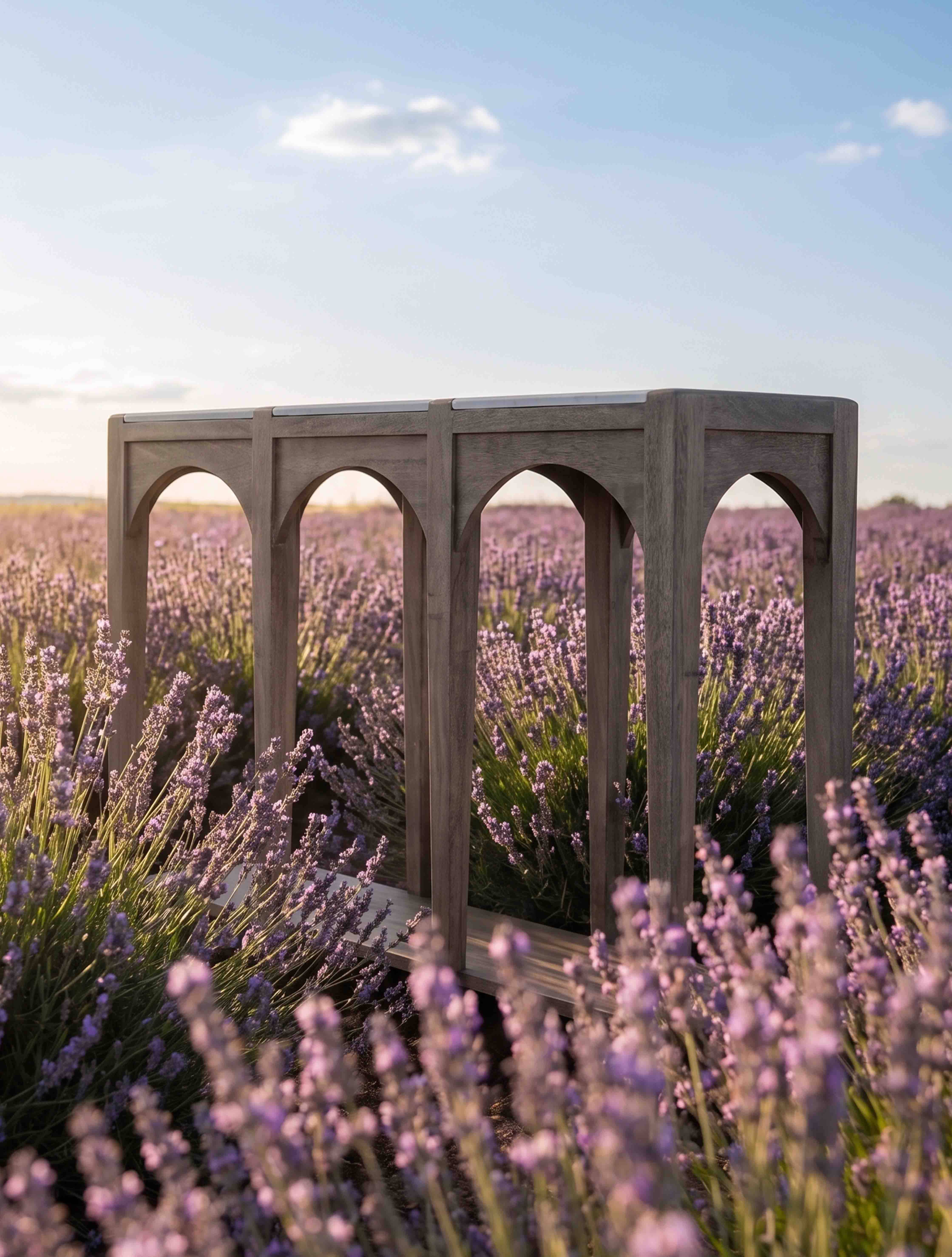 Table d'extérieur en bois gris avec pieds arqués sur fond de champ de lavande violet