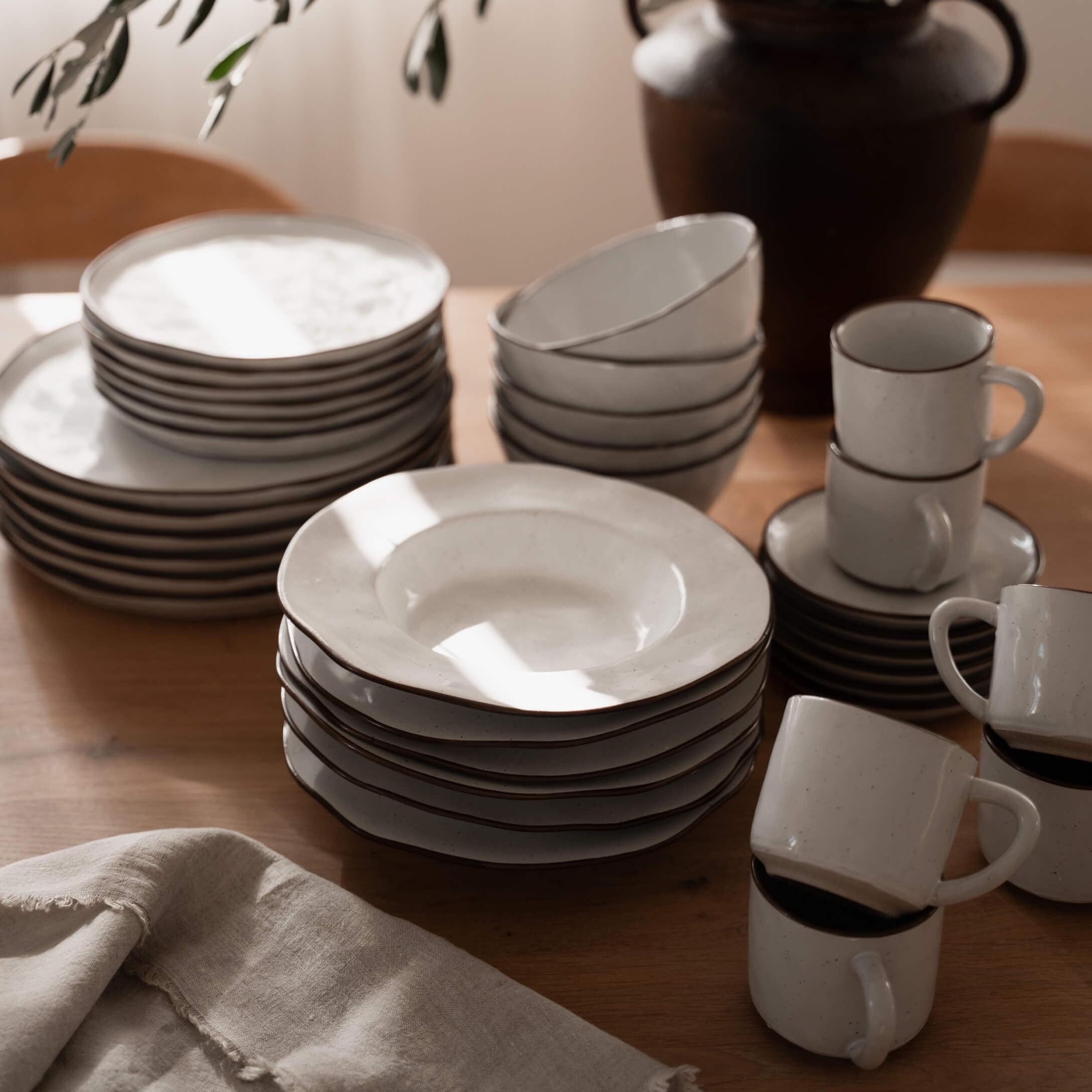 Service de vaisselle en céramique blanche avec bord brun sur table en bois, ustensiles de cuisine