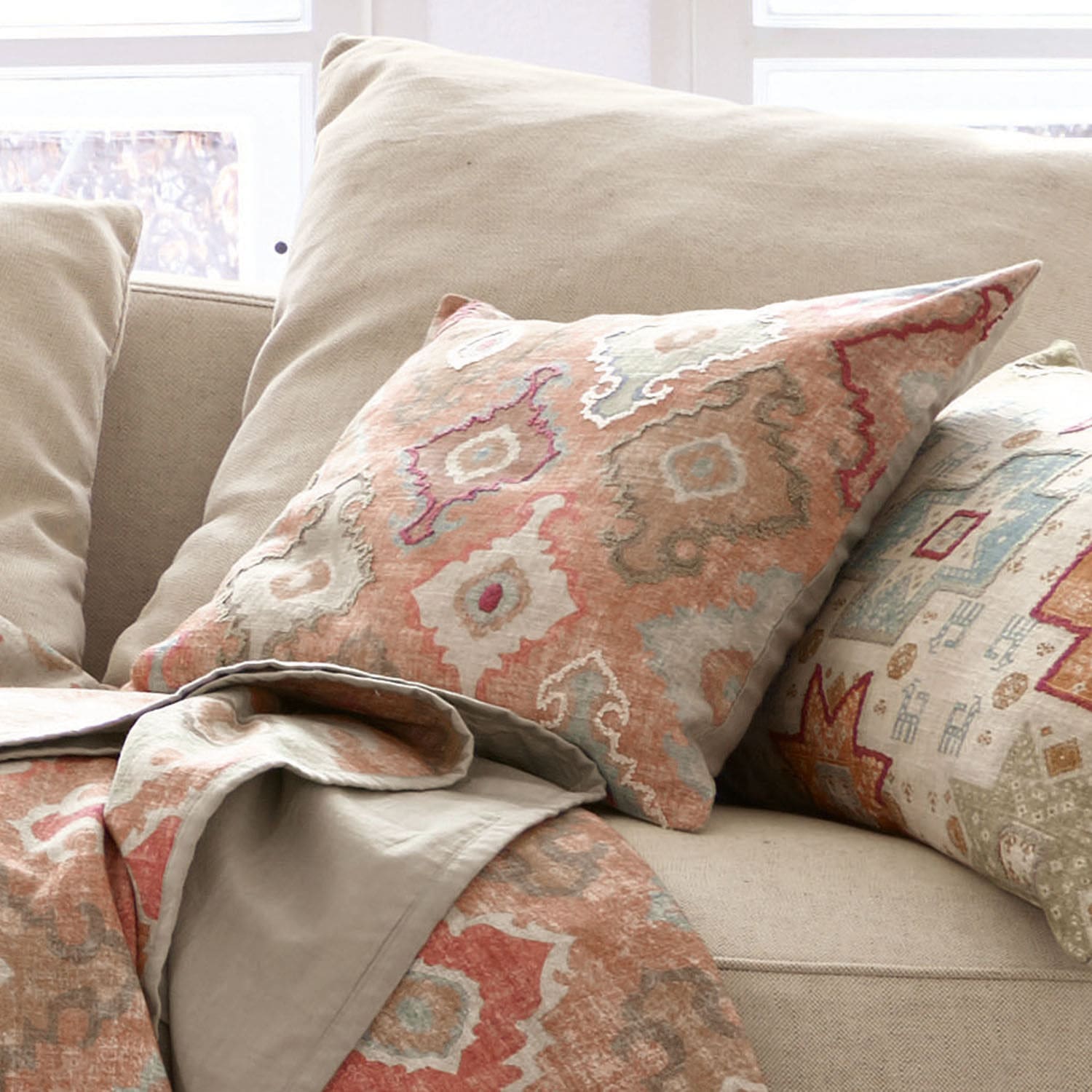 Coussin Donzy Canapé beige avec coussin décoratif et plaid aux motifs géométriques aux tons chauds