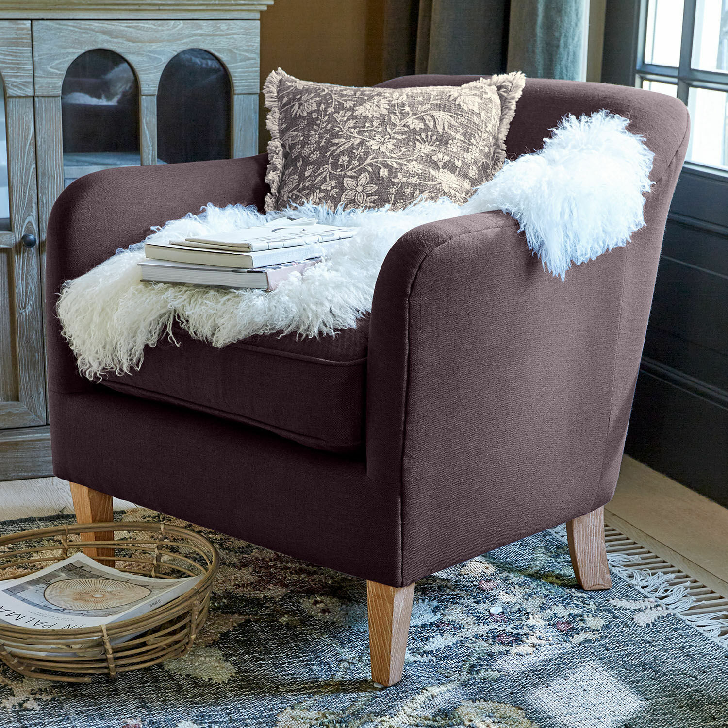 Fauteuil Jefferson Fauteuil marron en tissu avec pieds en bois, décoré d'un plaid en fausse fourrure blanche et d'un coussin à motifs